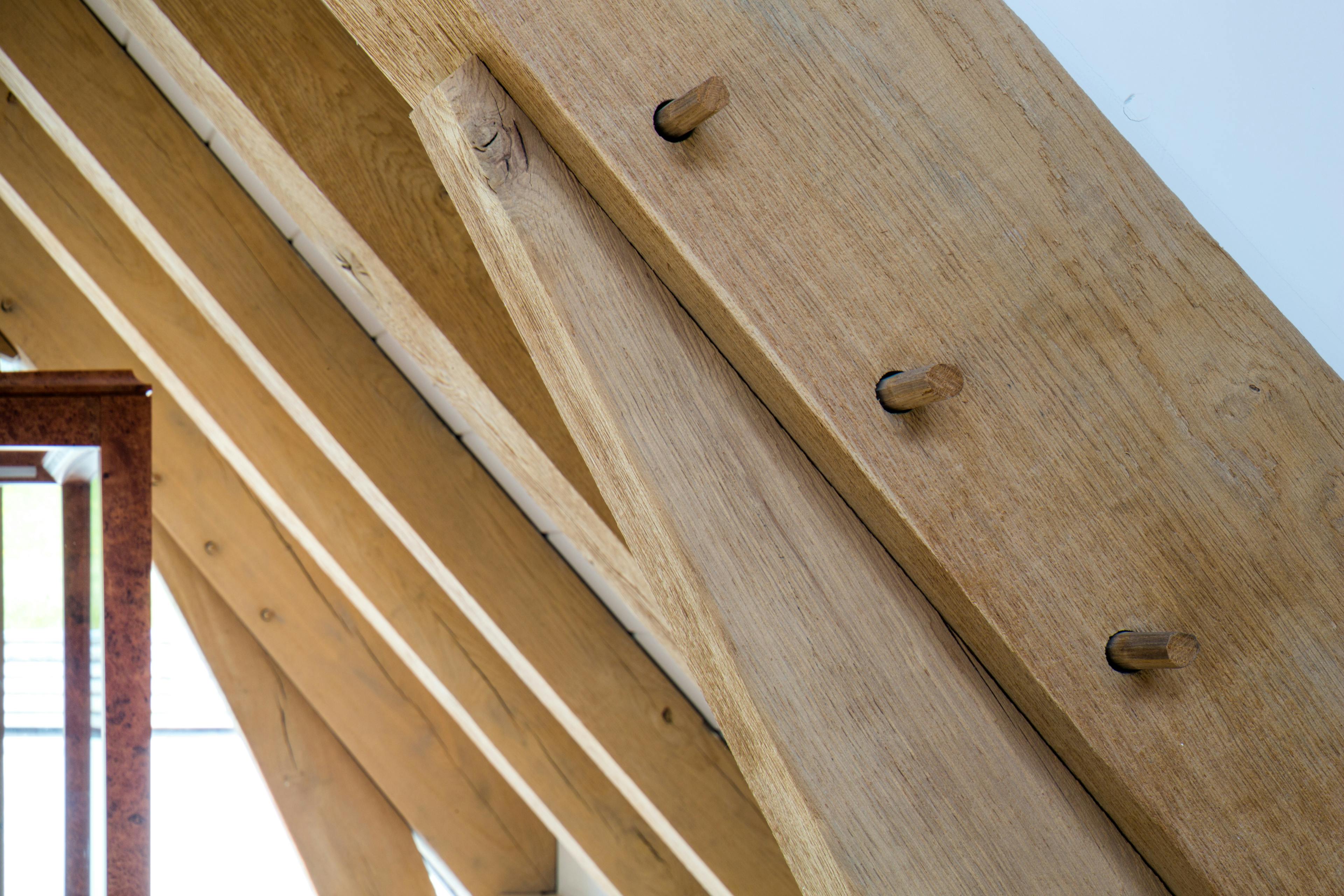 Close-up detail of an oak-framed beam featuring traditional joints secured with wooden pegs