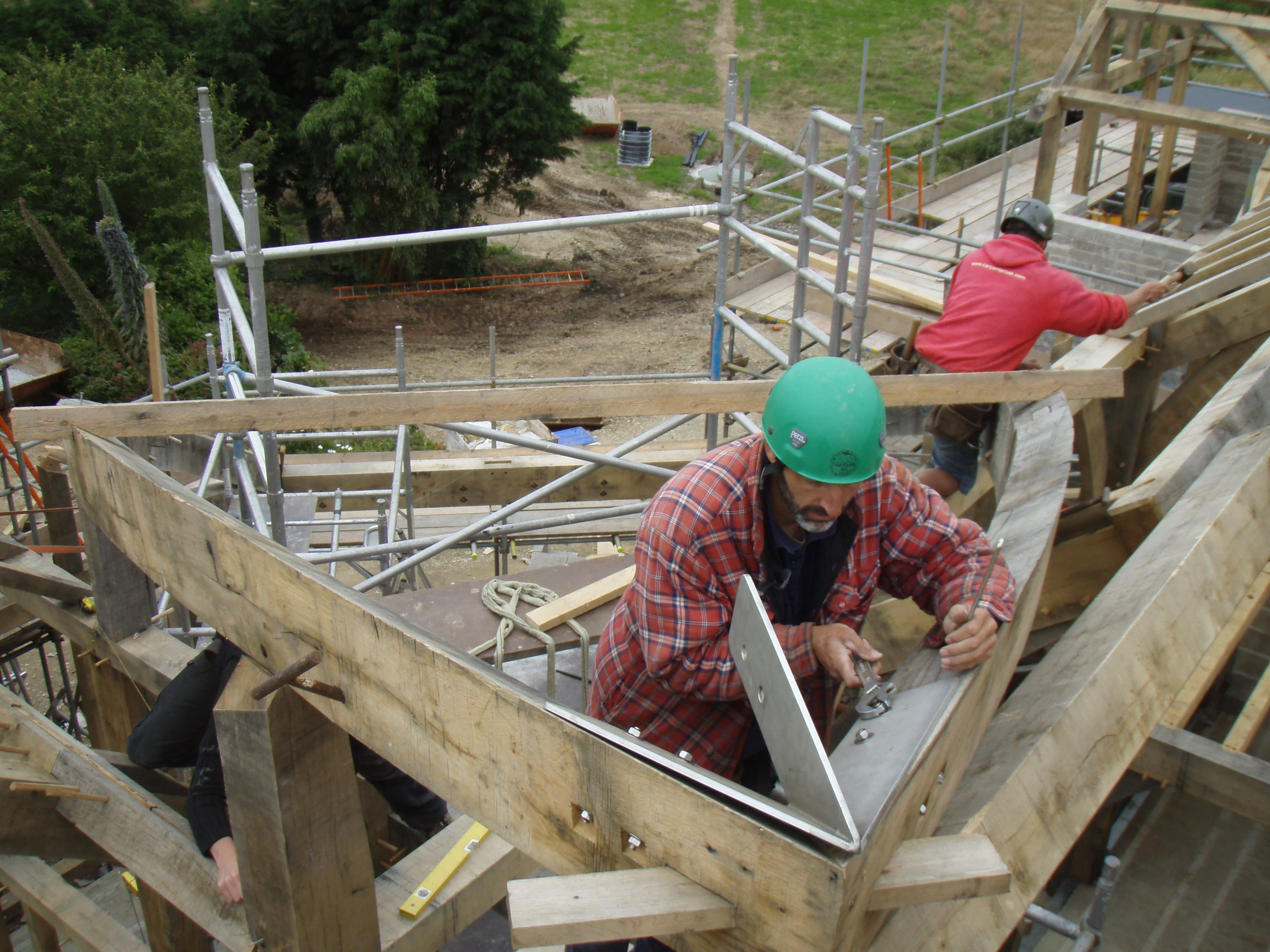 Carpenter installing a steel flitch plate onto curved oak beams at the construction site