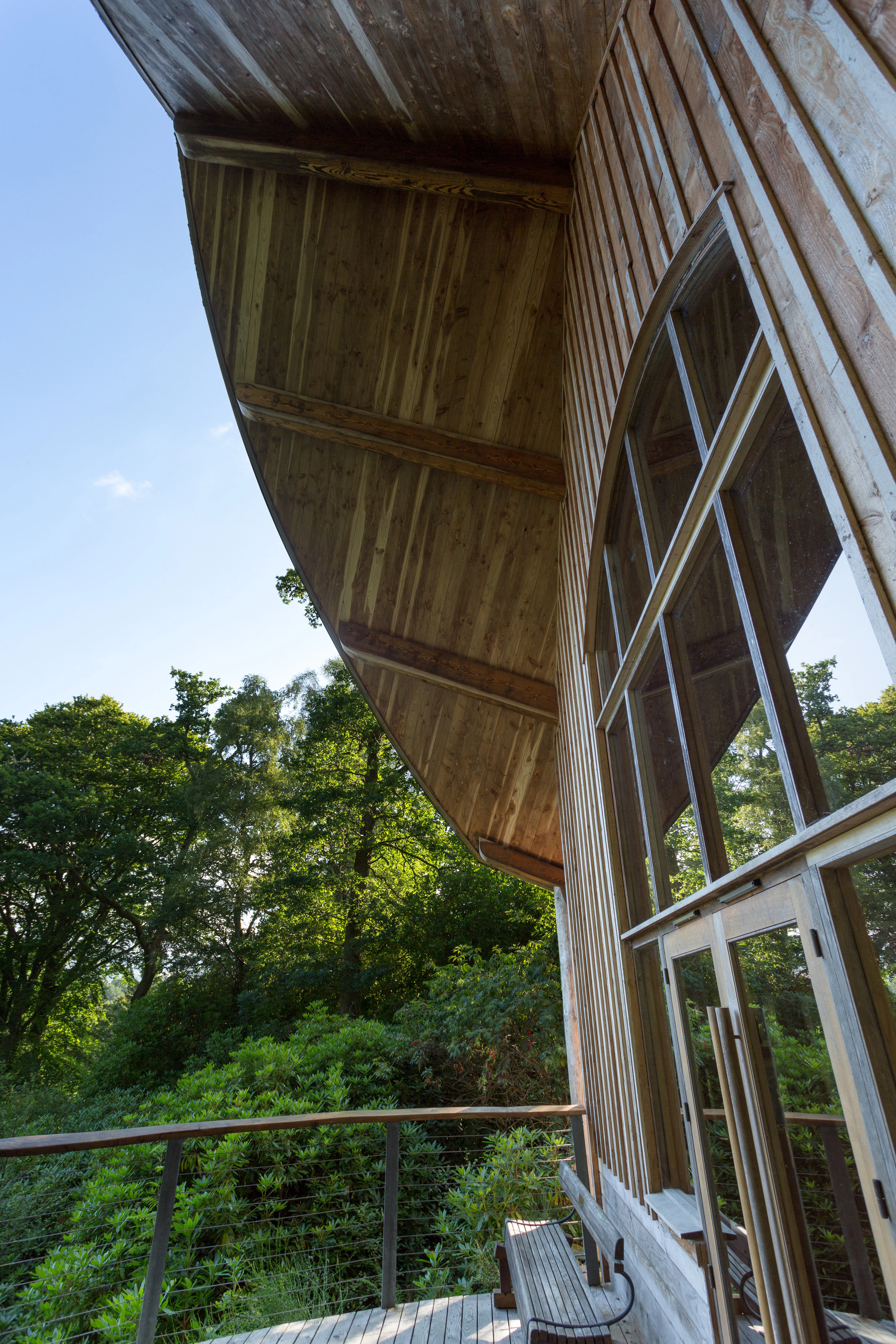 A wooden pavilion with an angled roof and large glazed doors and windows at the front