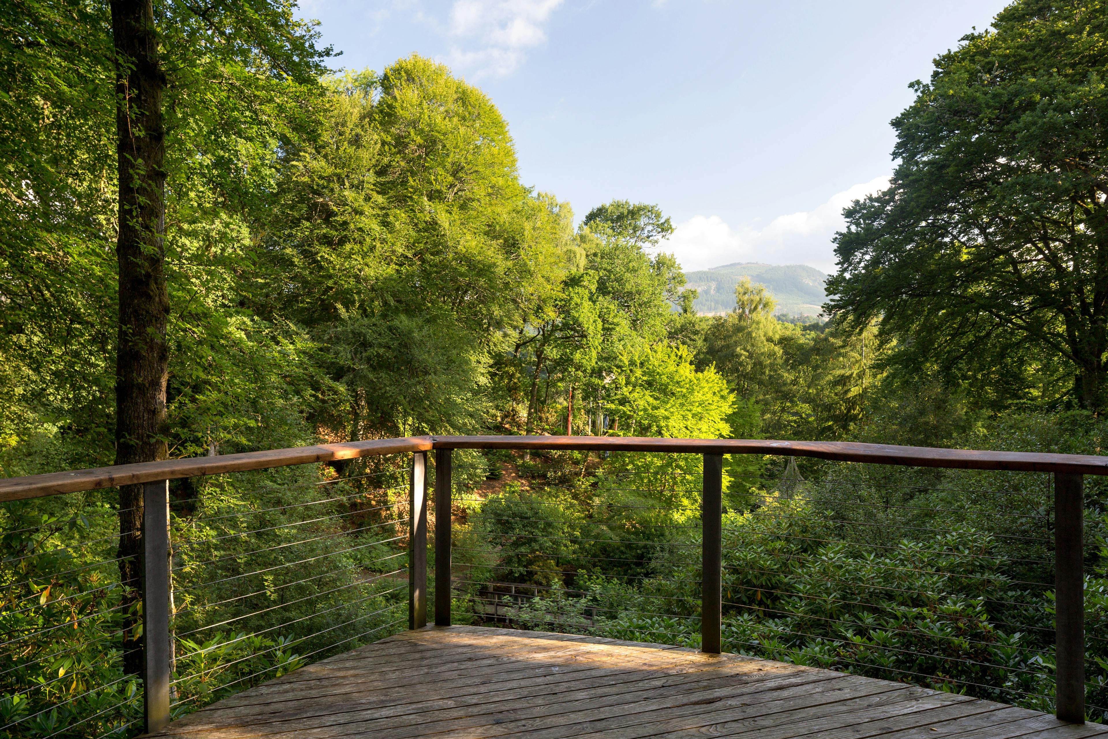 A wooden balcony overlooking a forest and distant views