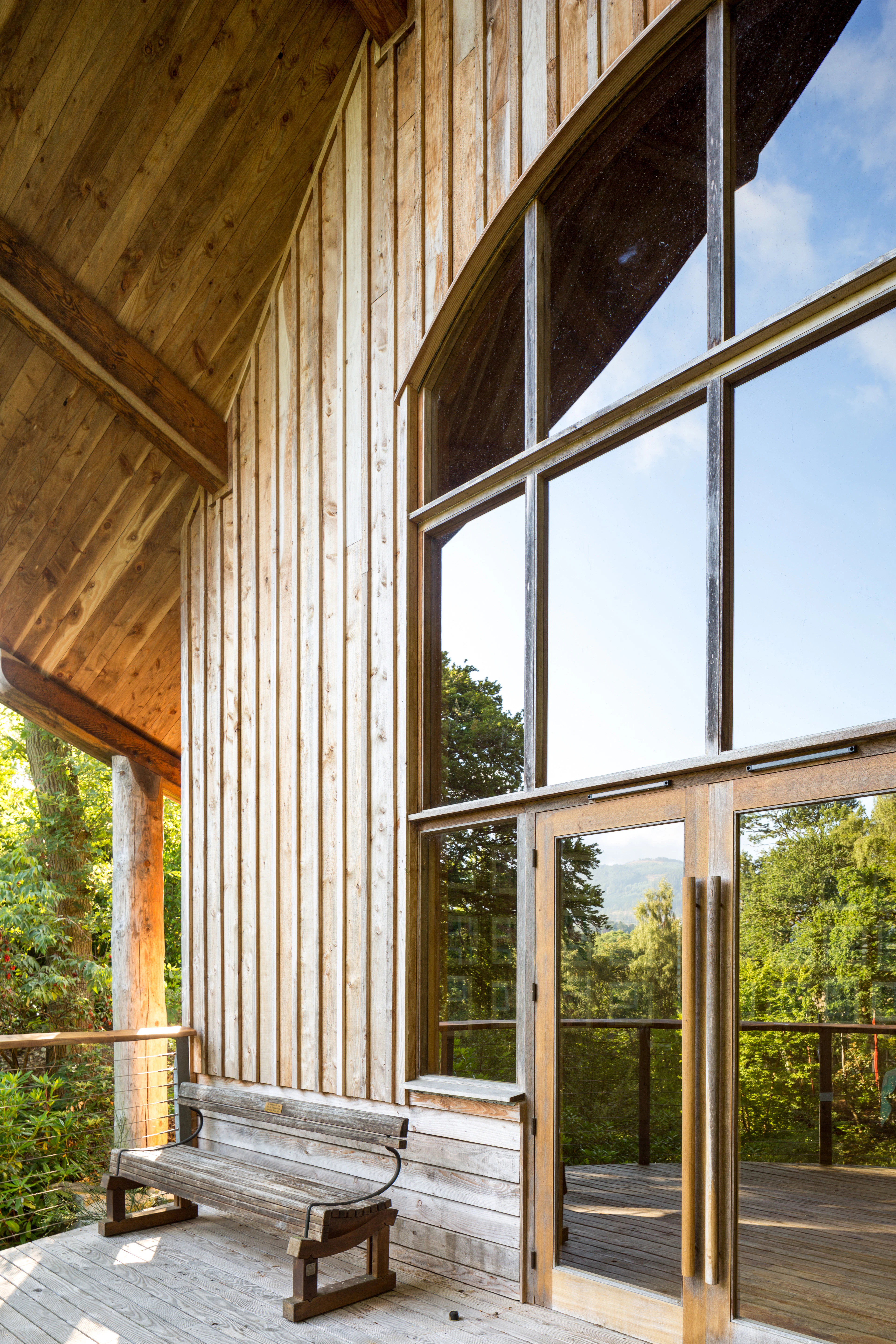 A wooden pavilion with an angled roof and large glazed doors and windows at the front