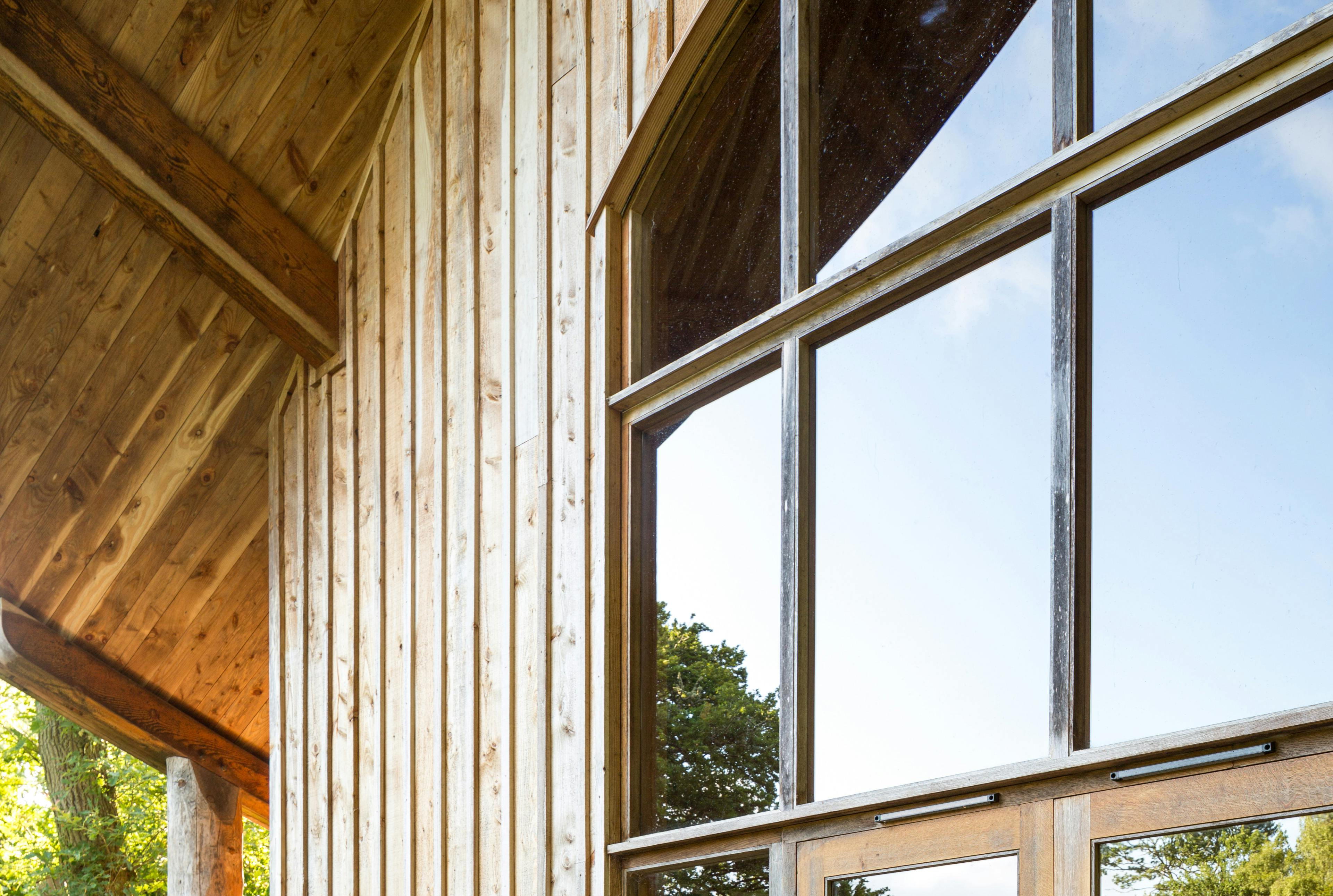 A wooden pavilion with an angled roof and large glazed doors and windows at the front