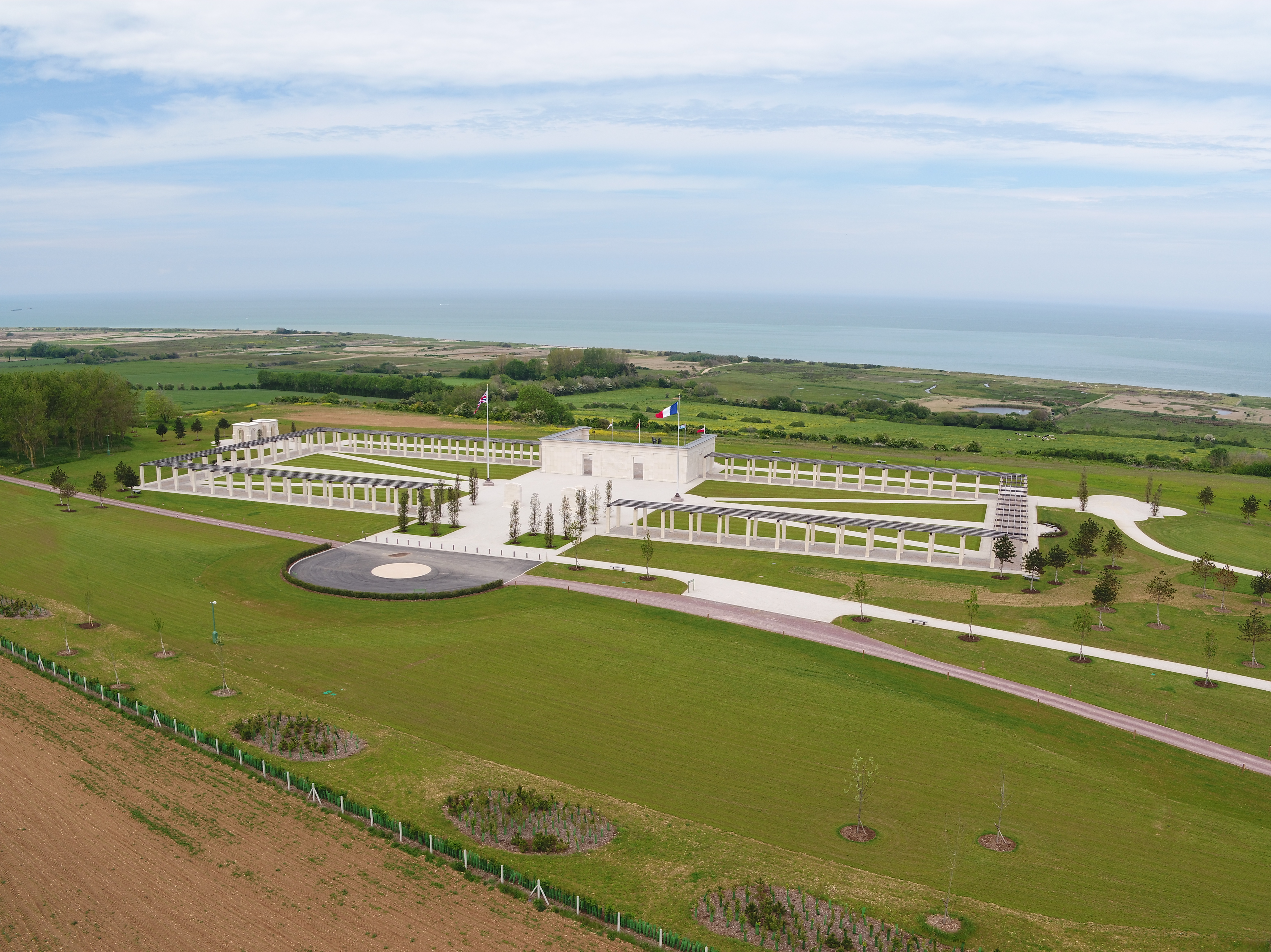An aerial view of the British Normandy Memorial with the blue sea and sky in the background