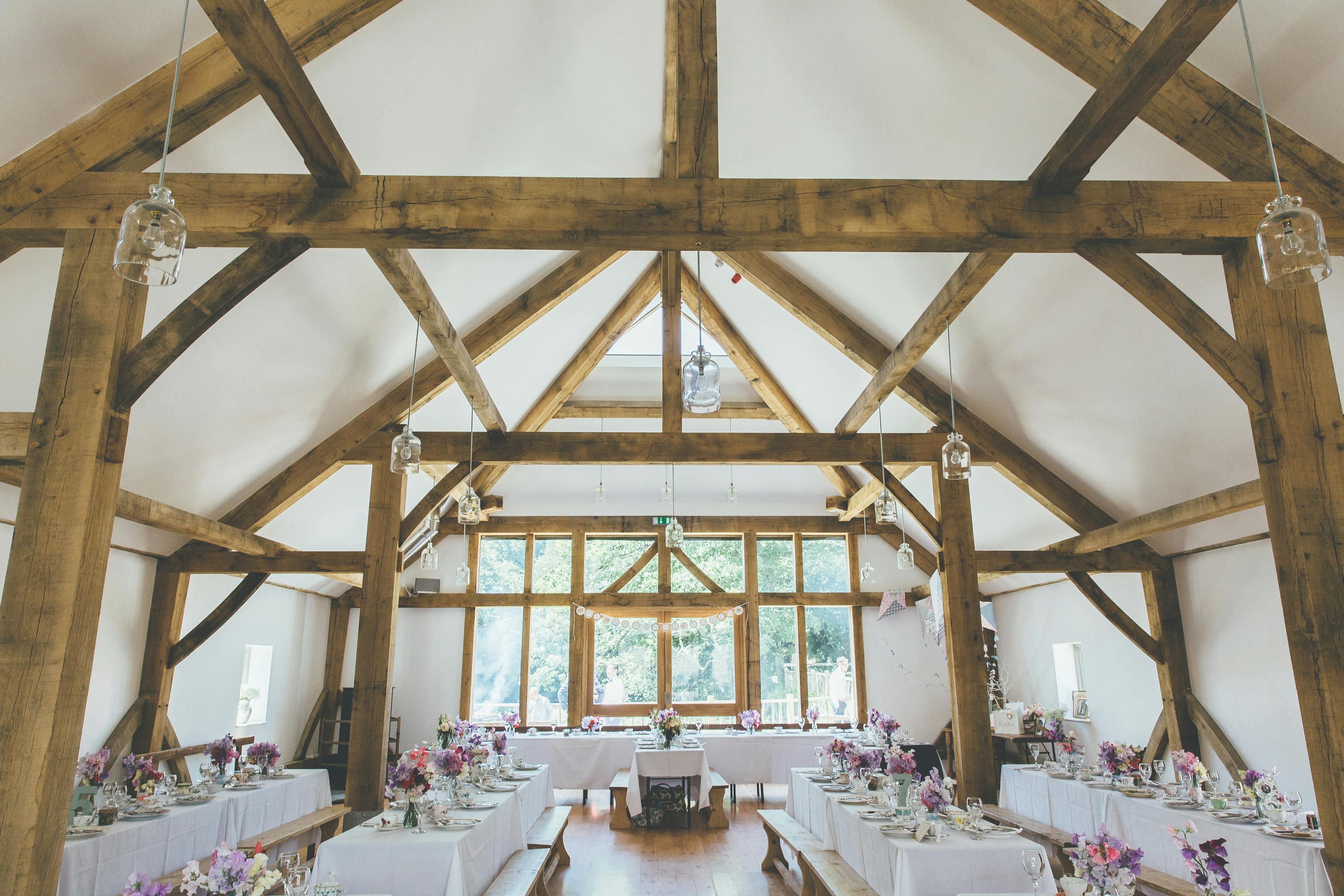 Tables are set for a wedding in an oak framed wedding barn