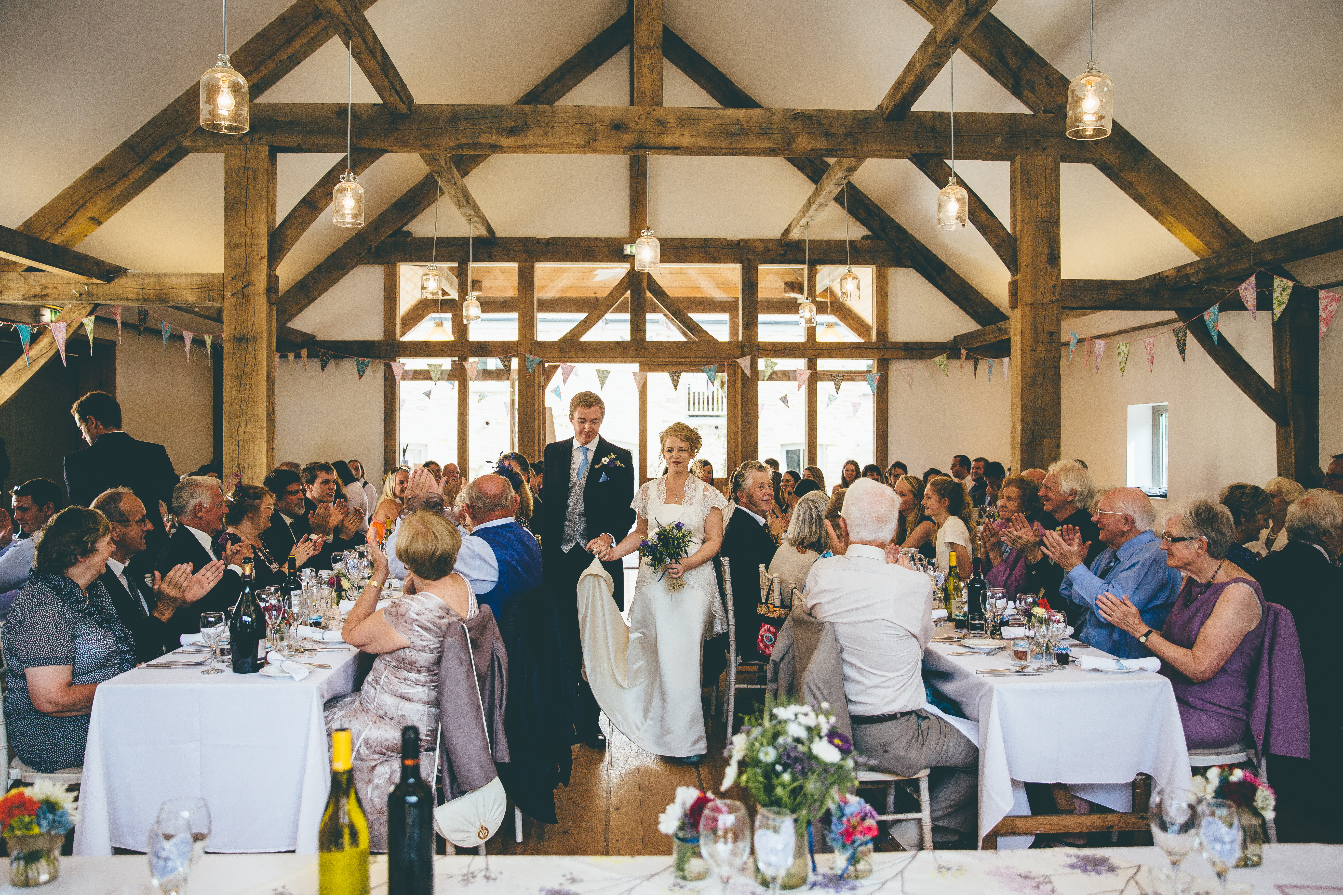 A bride and groom and wedding guests at a wedding in an oak framed wedding barn
