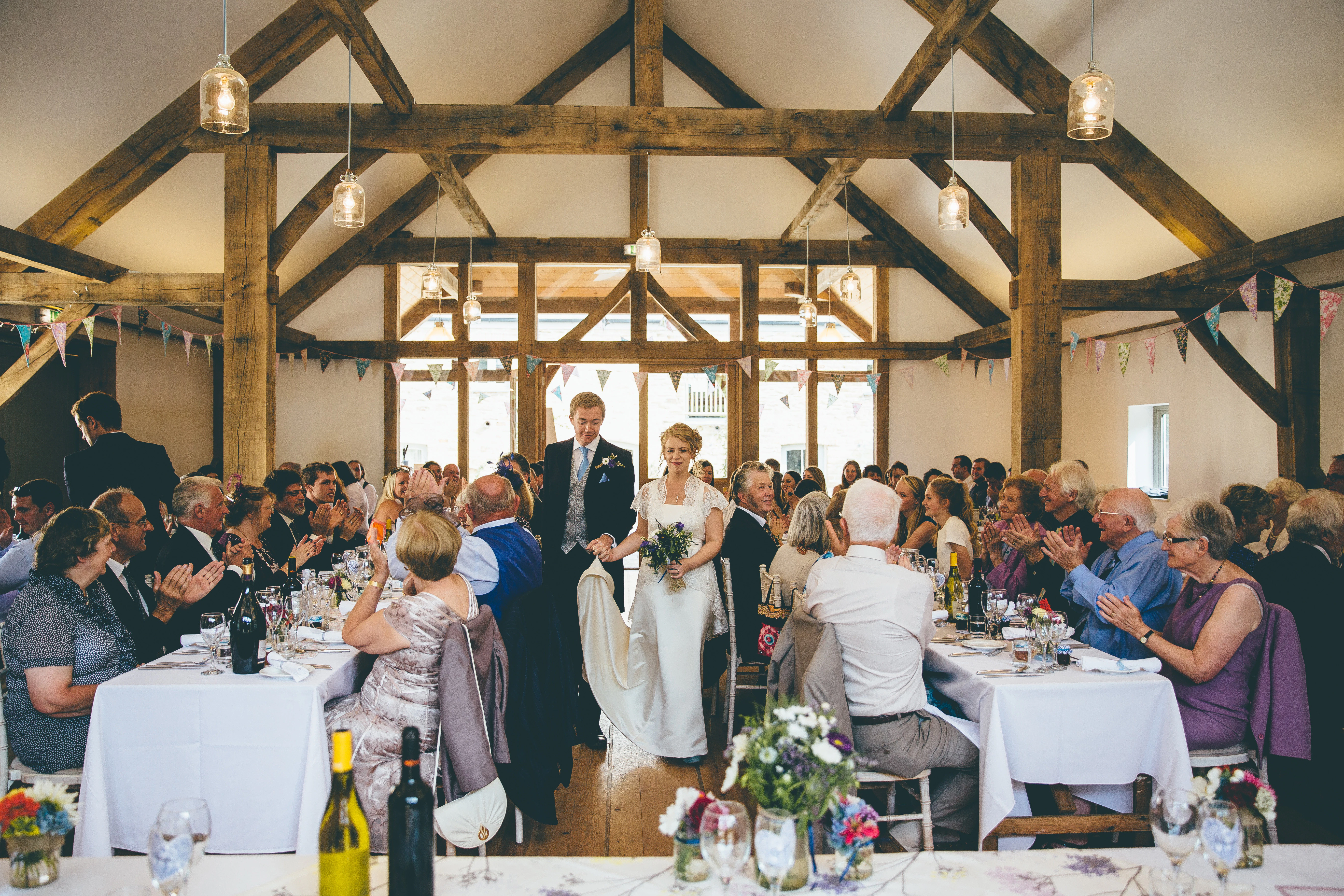 A bride and groom and wedding guests at a wedding in an oak framed wedding barn