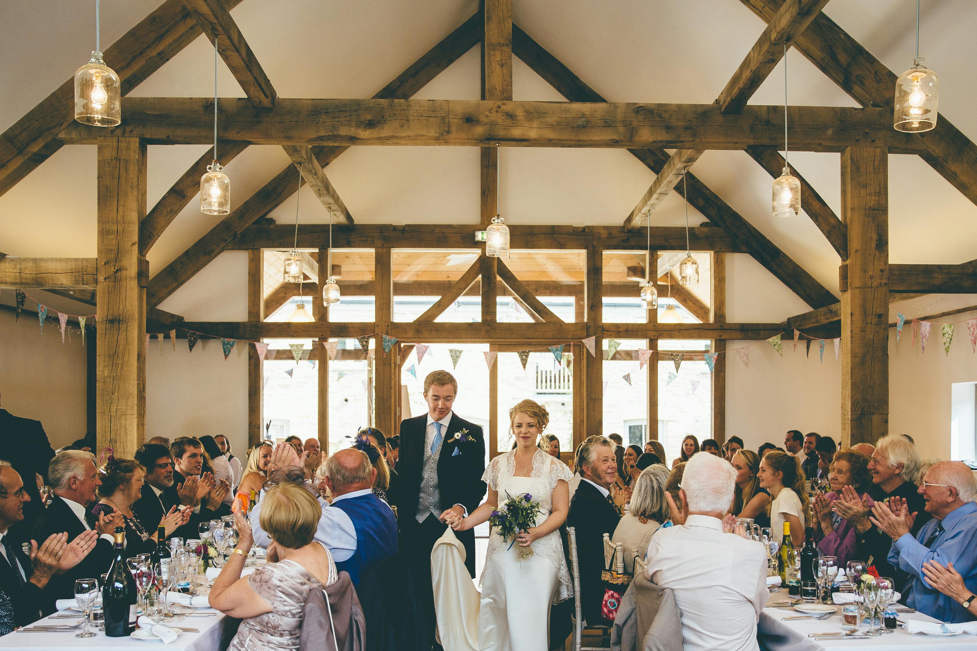 A bride and groom and wedding guests at a wedding in an oak framed wedding barn