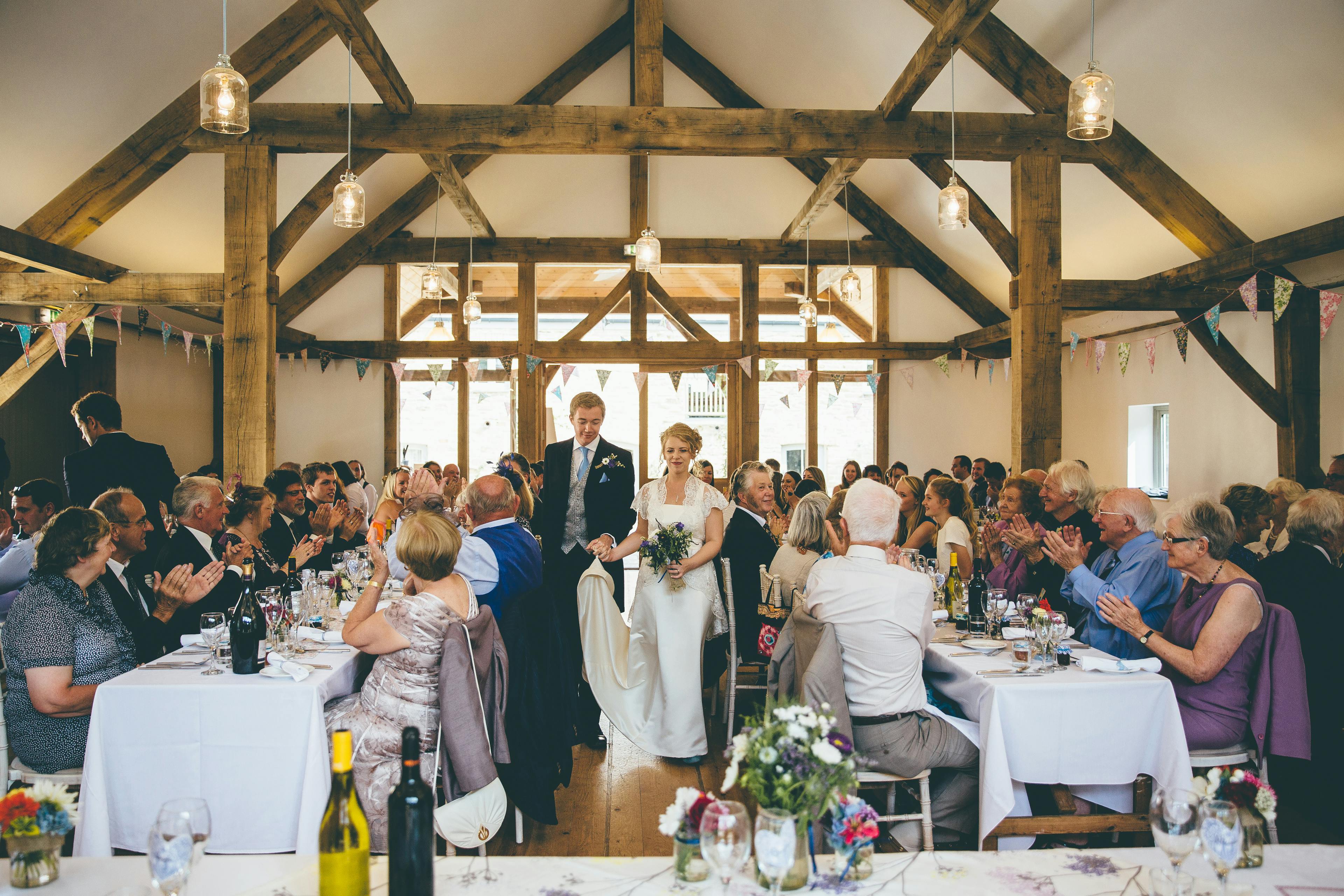 A bride and groom and wedding guests at a wedding in an oak framed wedding barn