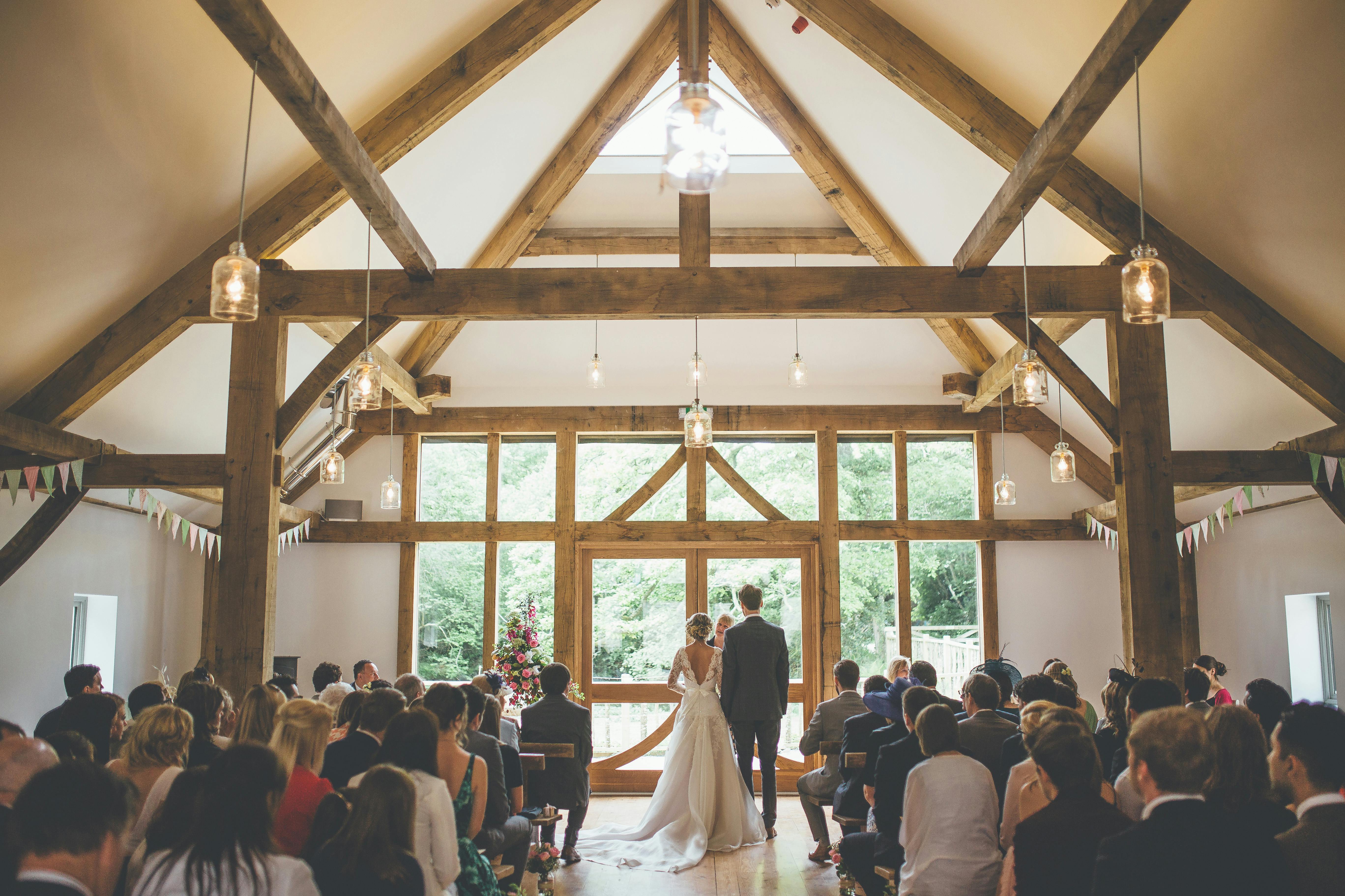 A bride and groom getting married in front of wedding guests at a wedding in an oak framed wedding barn