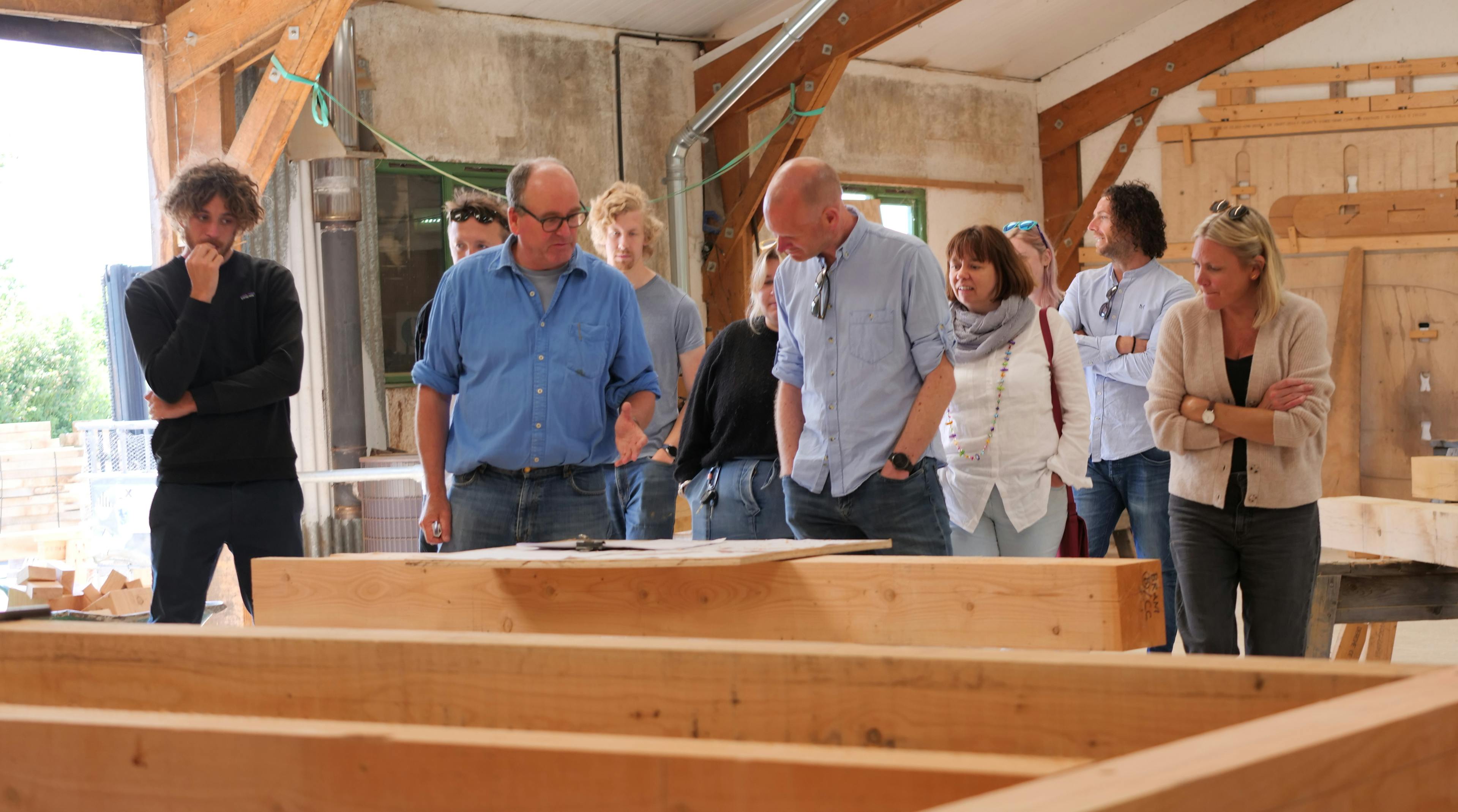 A group of people on a tour in a timber framing workshop