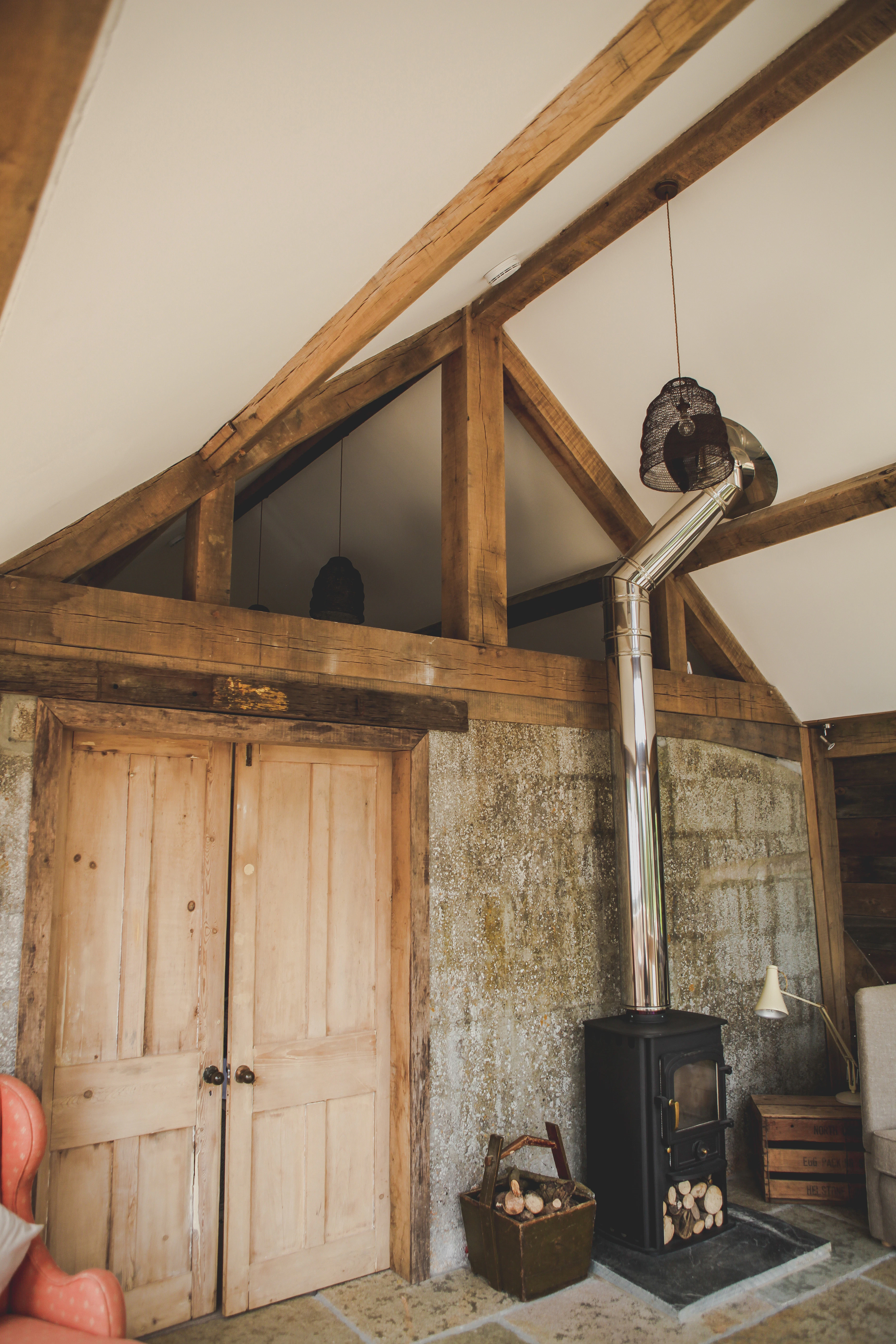 A log burner inside an oak framed cabin with a direct glazing