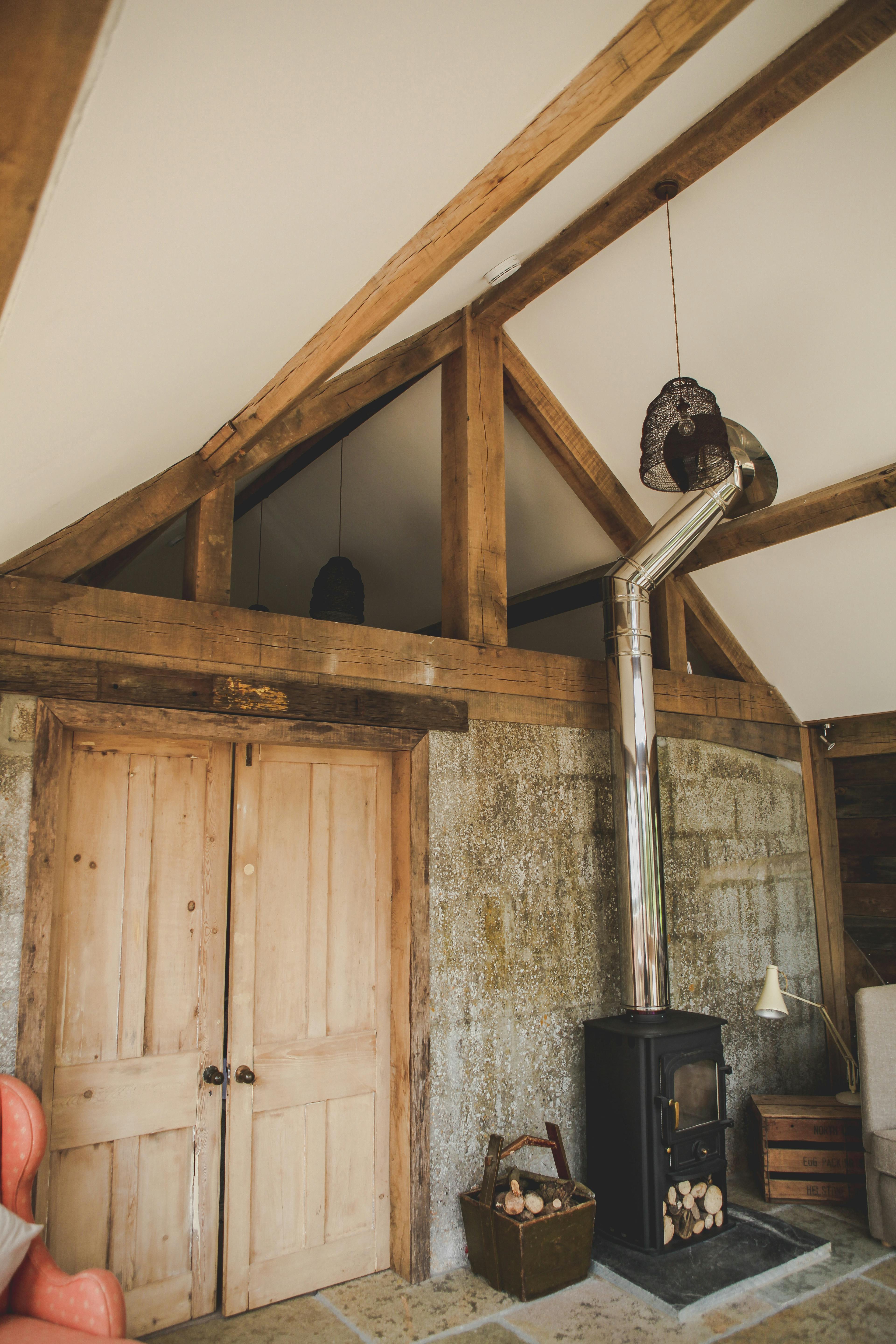 A log burner inside an oak framed cabin with a direct glazing