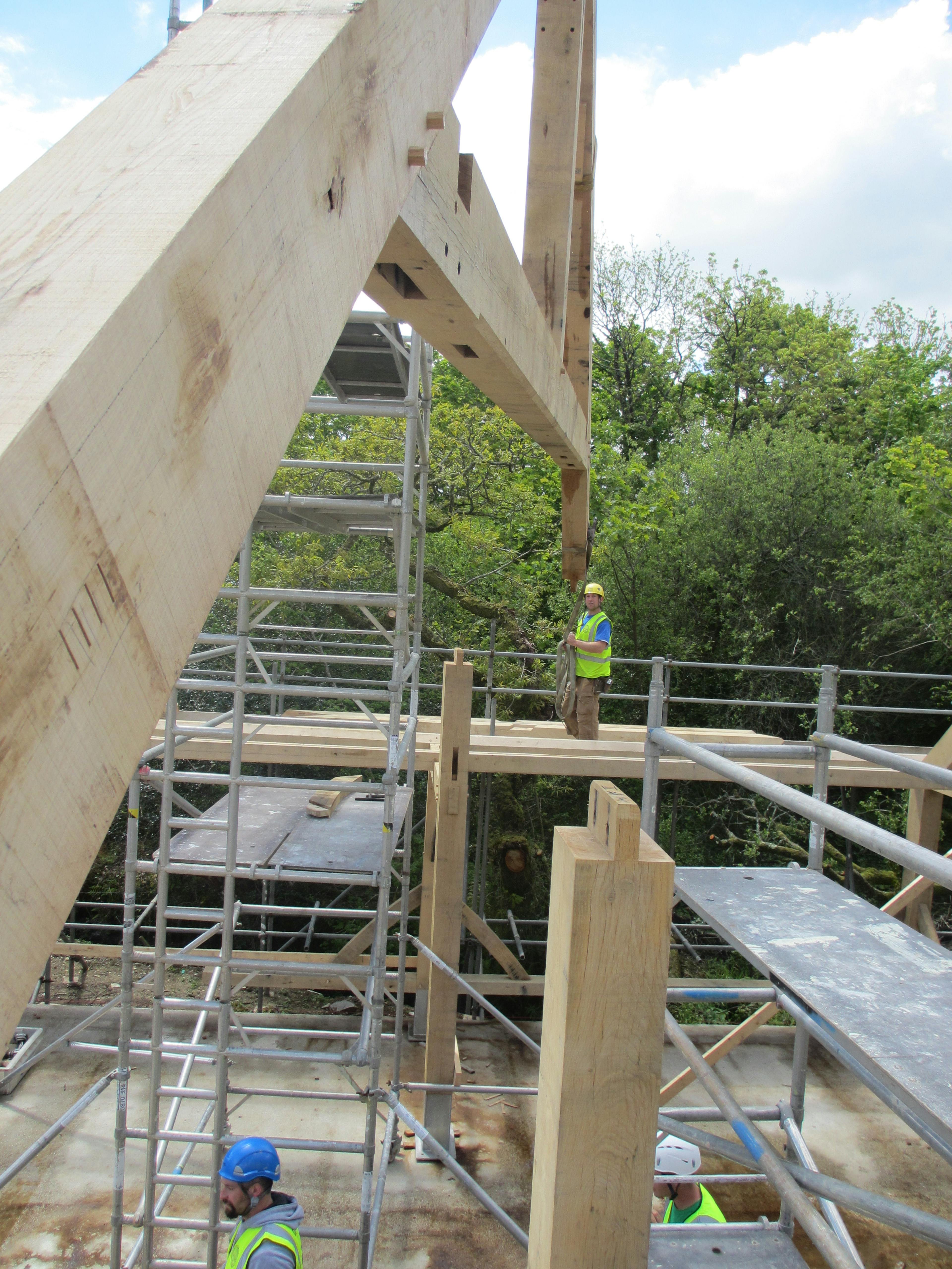 On a construction site the frame for an oak framed wedding barn is installed by a crane