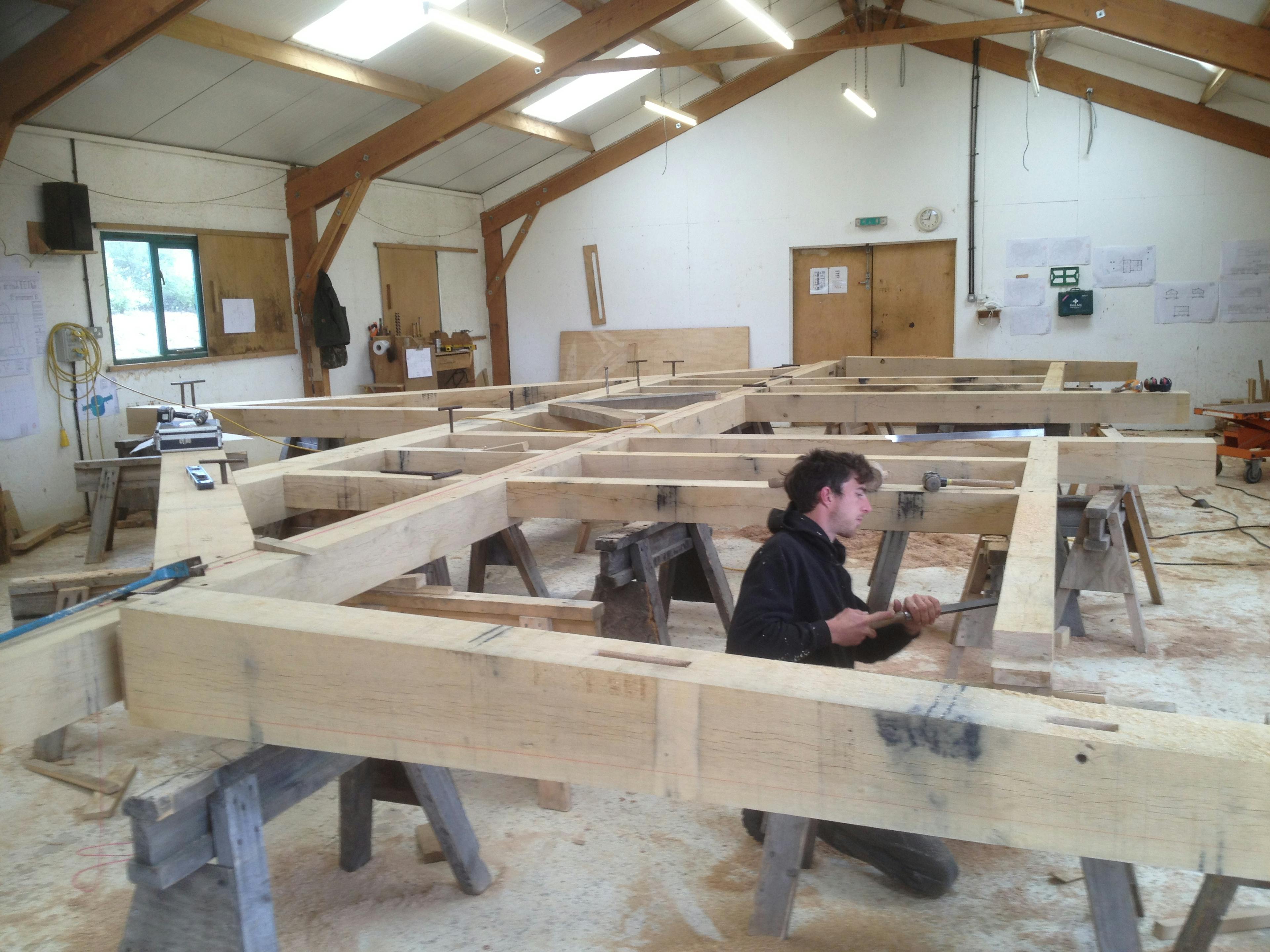 A large oak frame being manufactured by hand by a carpenter in a workshop