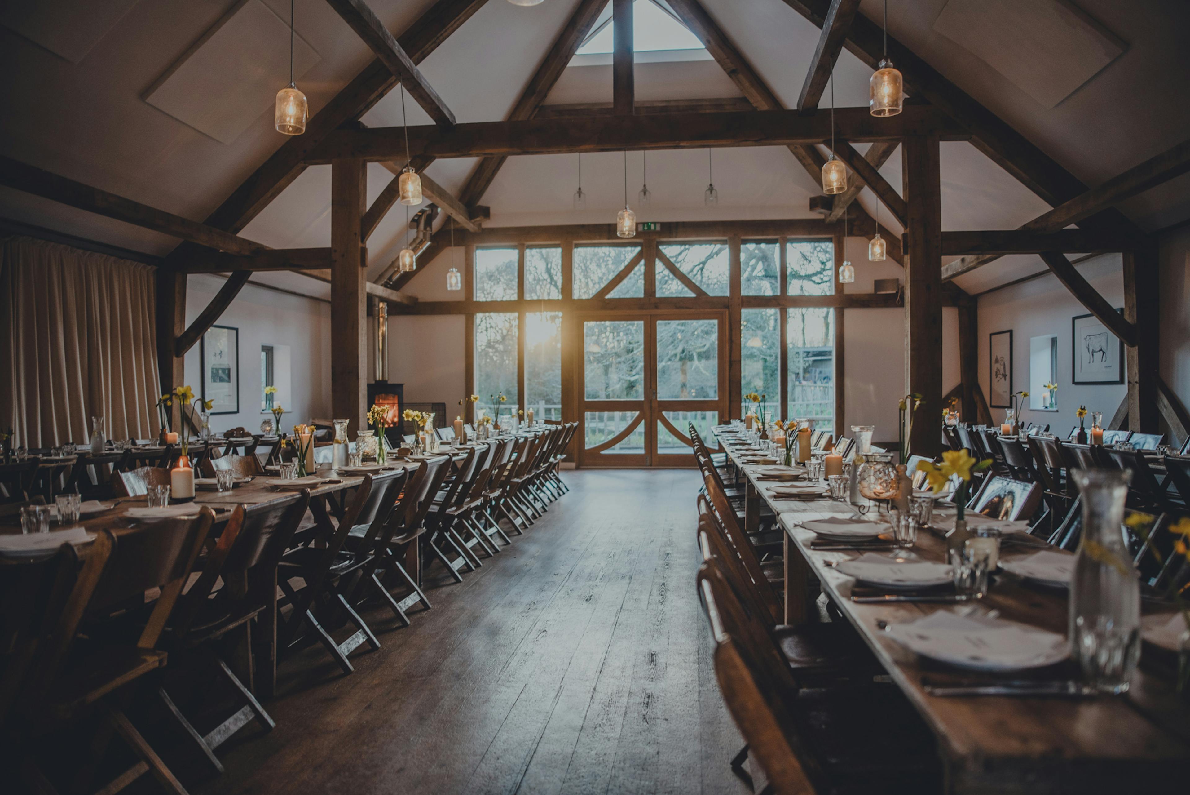 Tables are set for a wedding in an oak framed wedding barn
