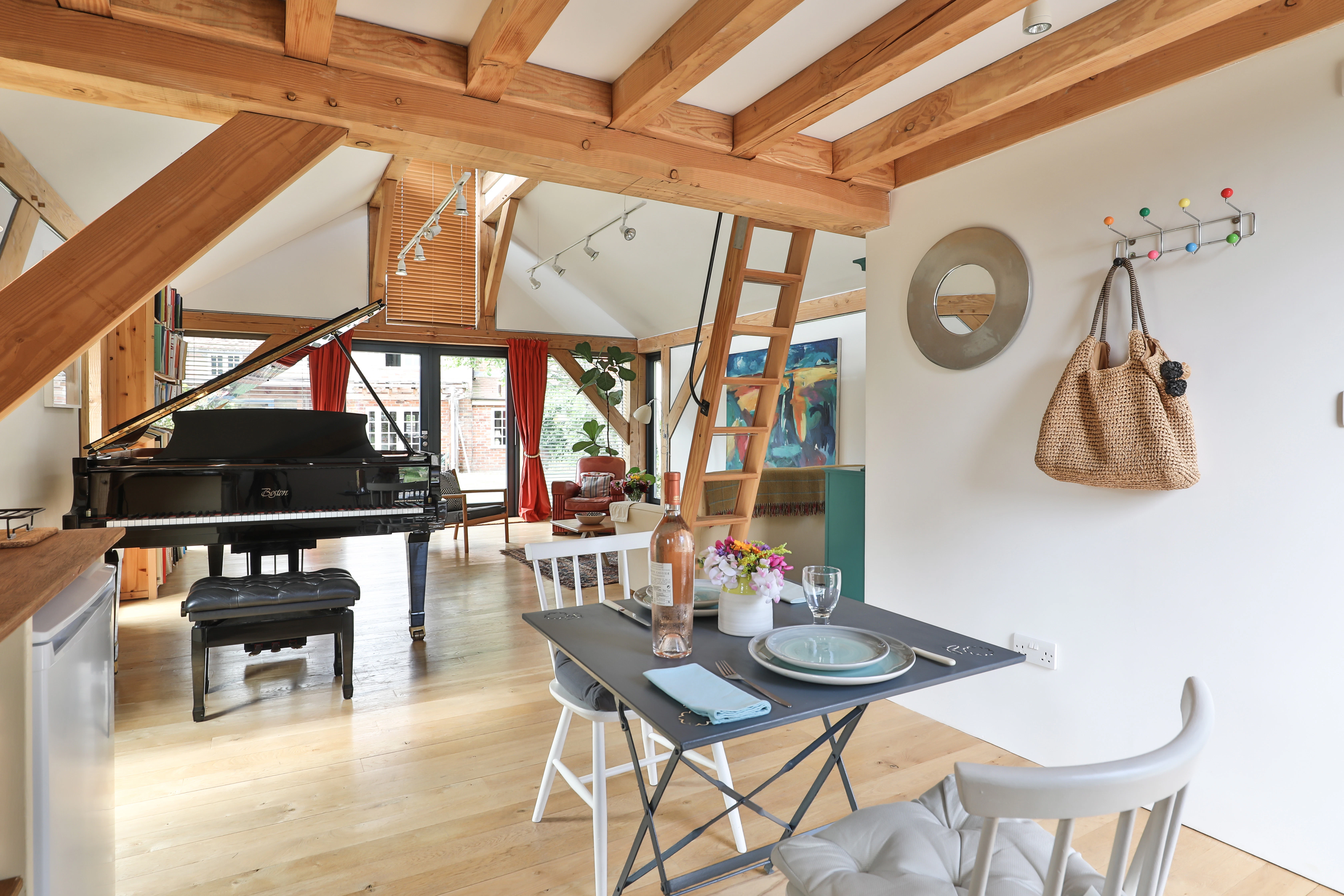 A dining table and chairs and black grand piano in an open plan Douglas fir framed living room