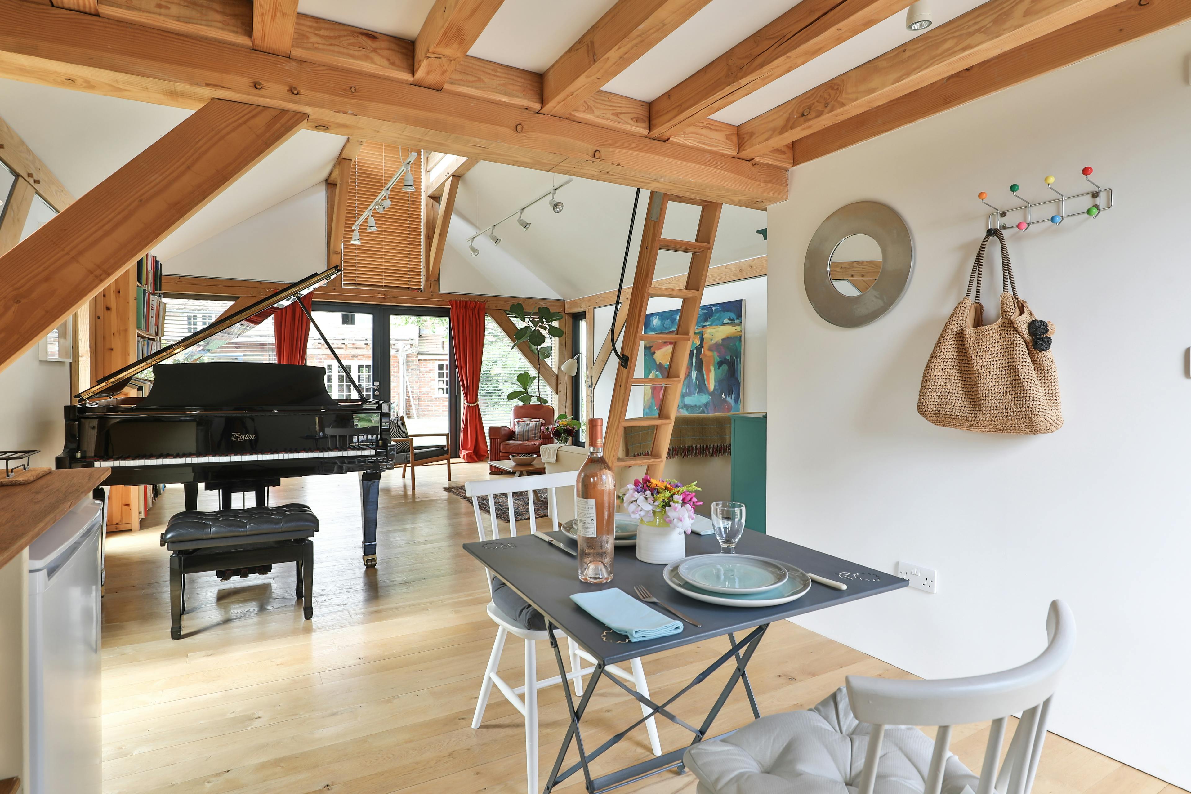 A dining table and chairs and black grand piano in an open plan Douglas fir framed living room