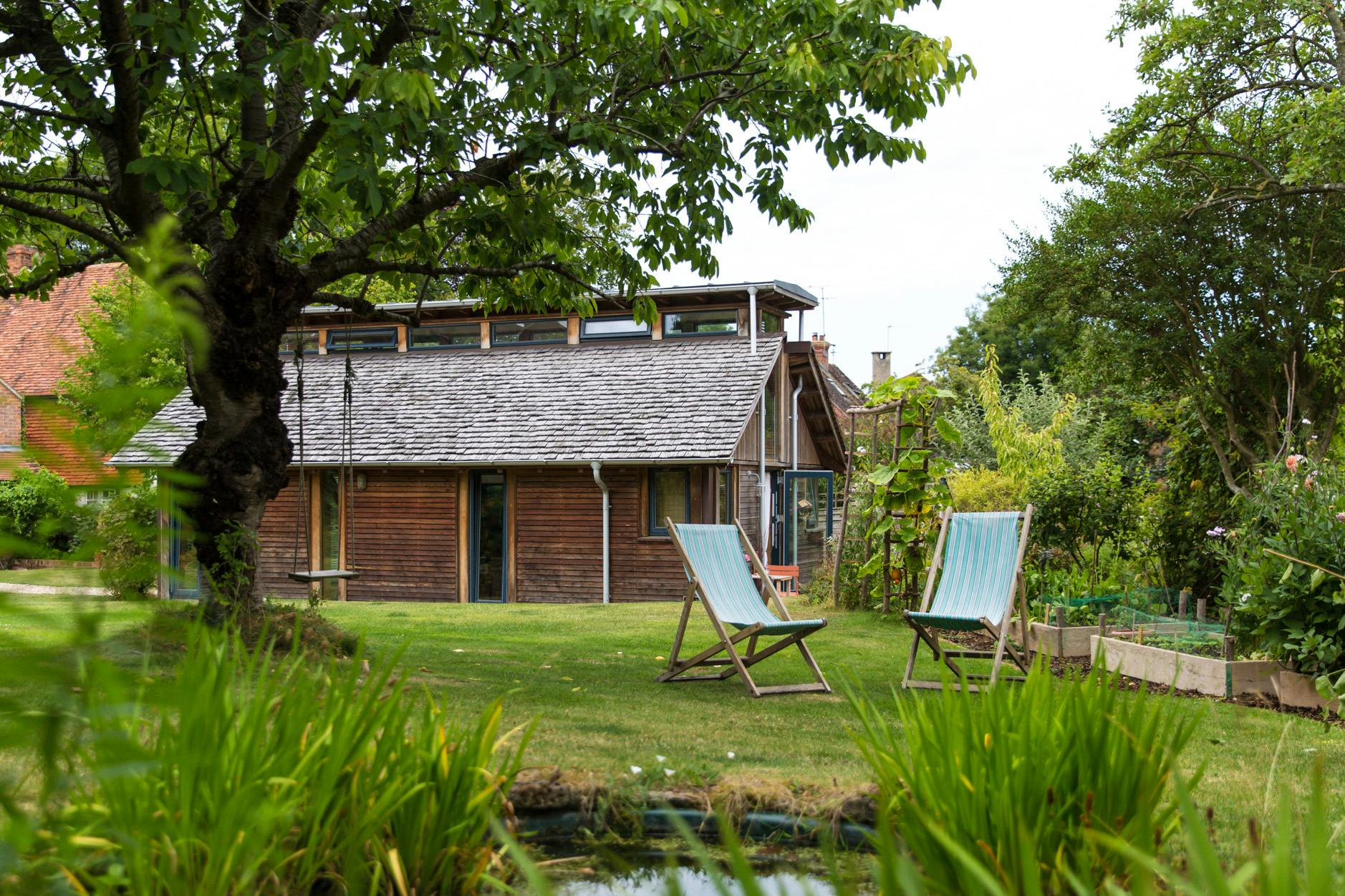 The side of a Douglas fir framed building with cedar cladding and oak shingles with a garden around it