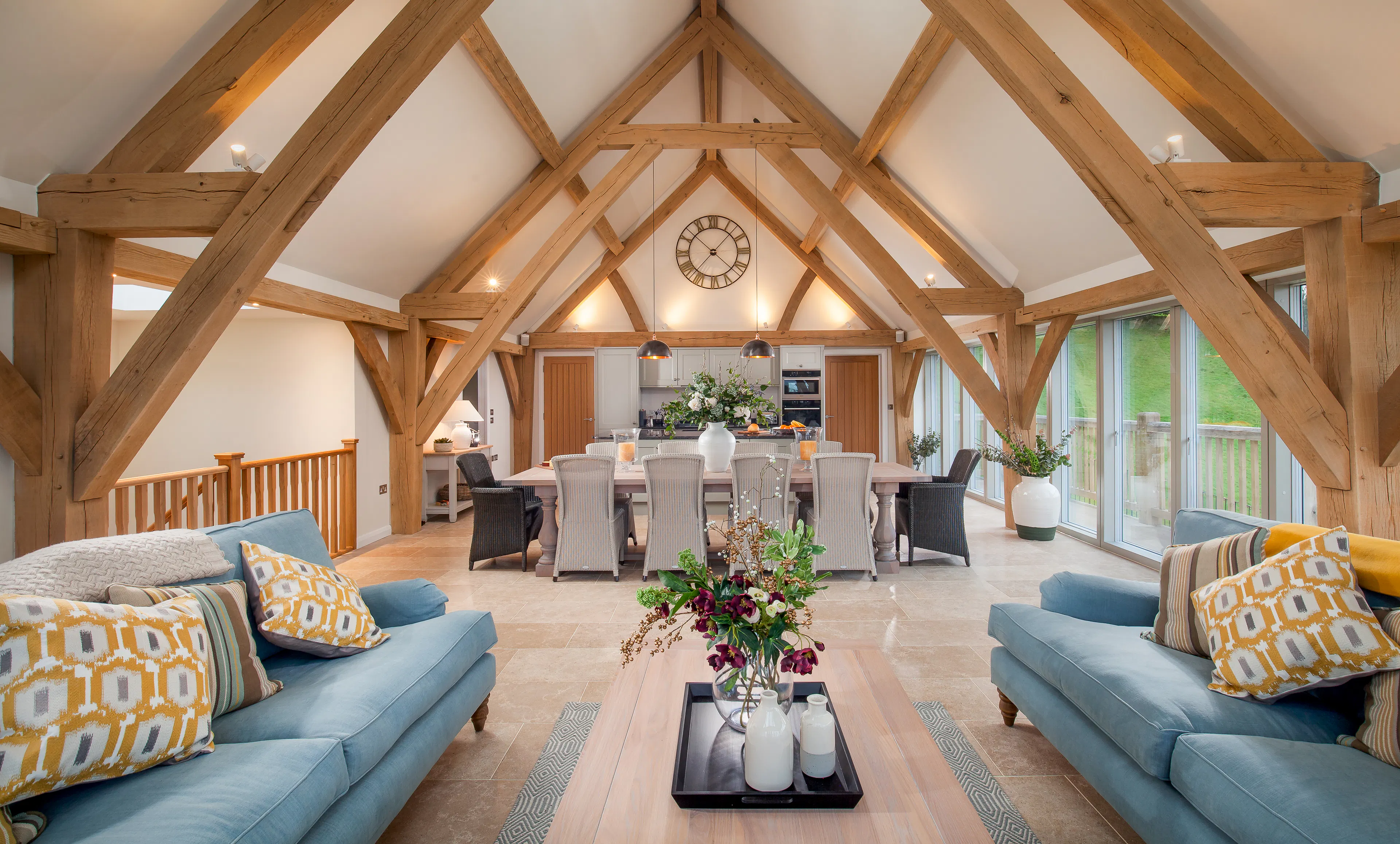 A sitting area with sofas, dining area and kitchen in a vaulted an oak framed open plan living area