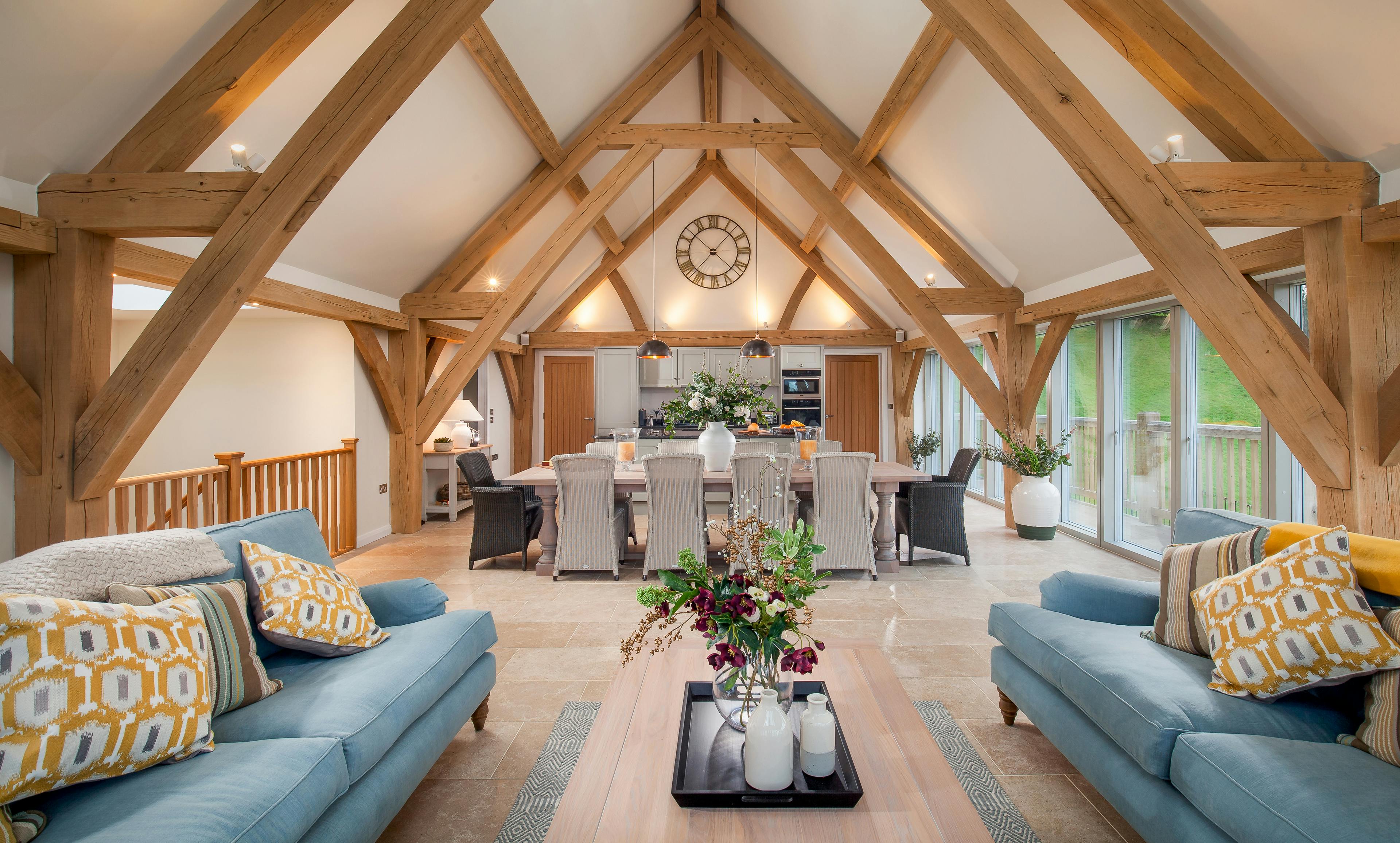 A sitting area with sofas, dining area and kitchen in a vaulted an oak framed open plan living area
