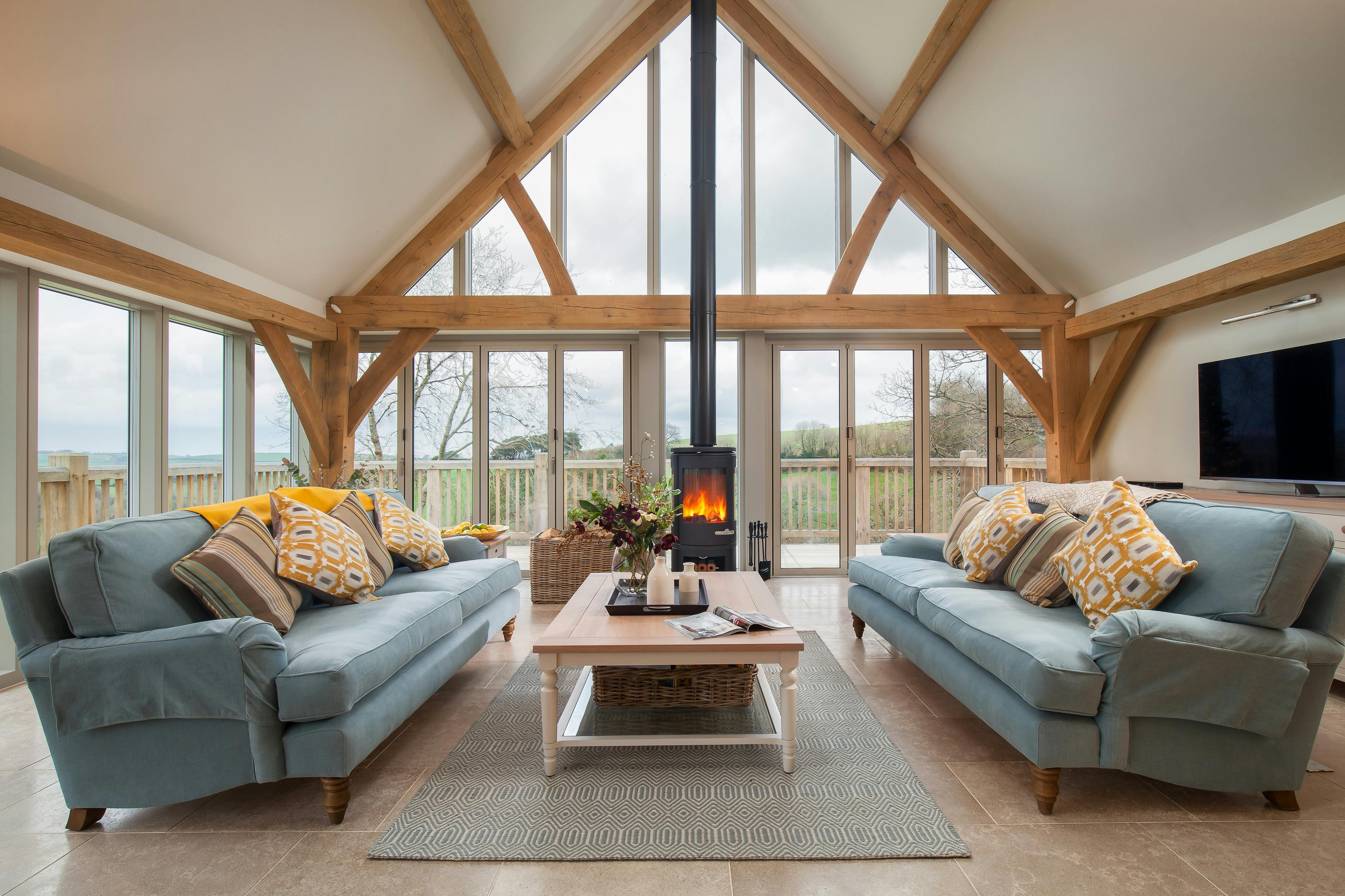 A sitting area with sofas and log burner in a vaulted an oak framed open plan living area