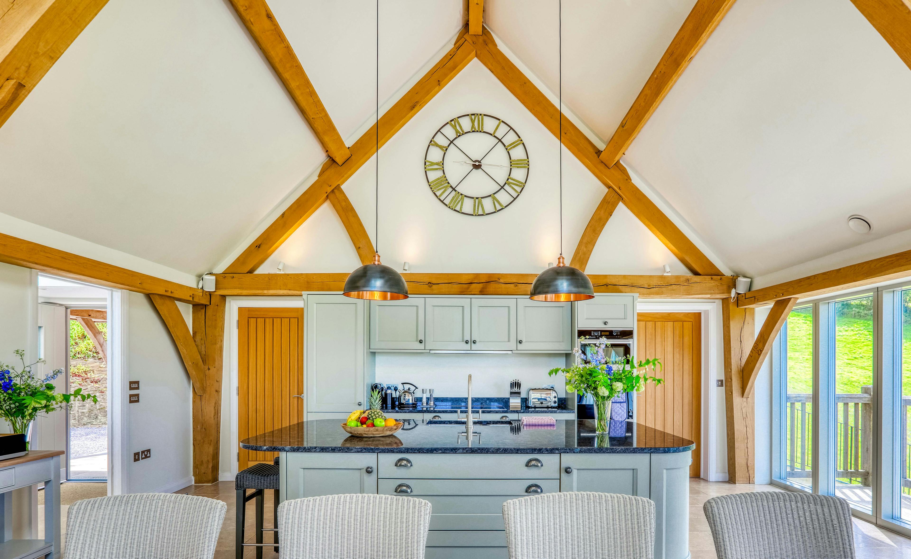 A dining area area and kitchen in a vaulted an oak framed open plan living area