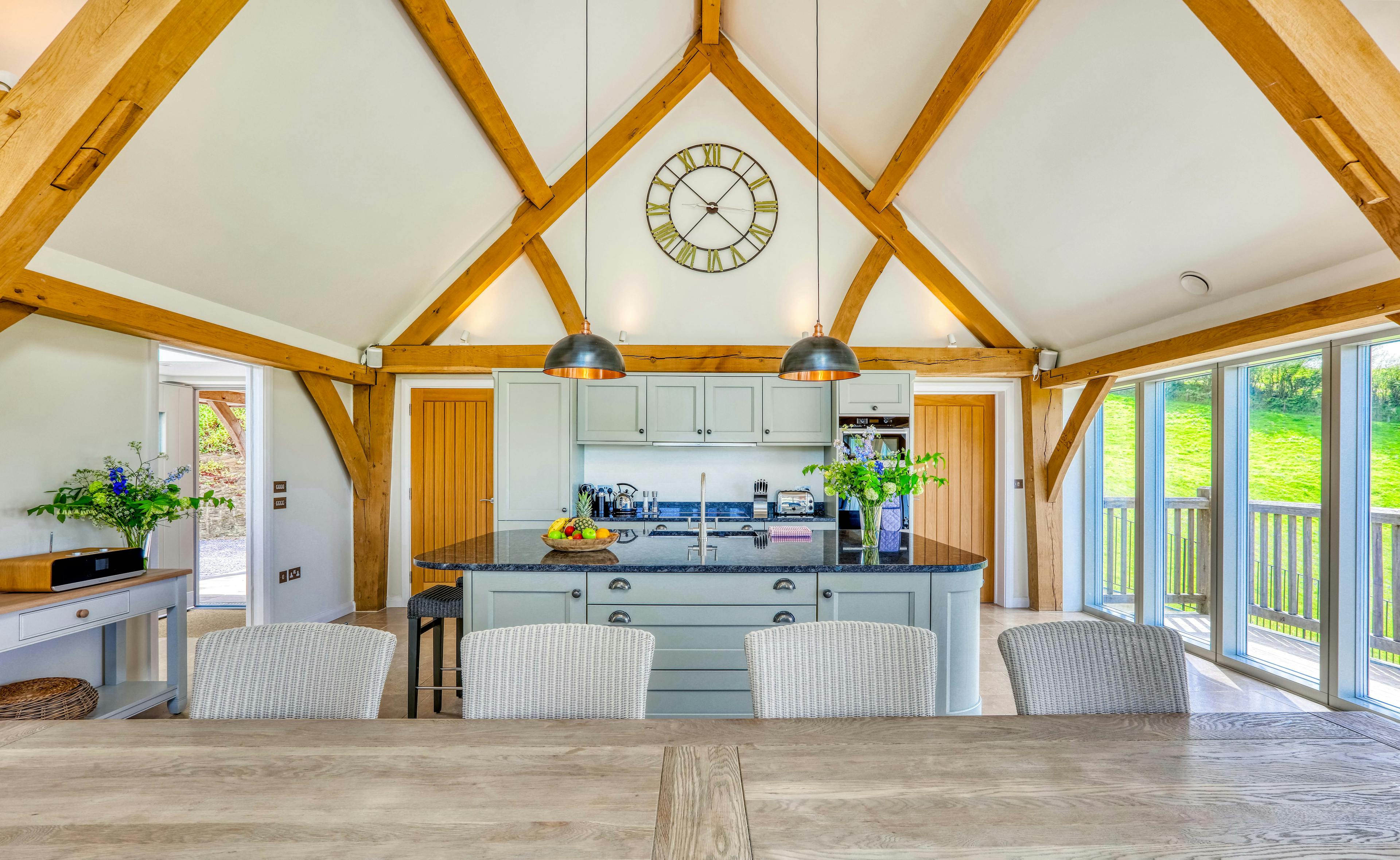 A dining area area and kitchen in a vaulted an oak framed open plan living area