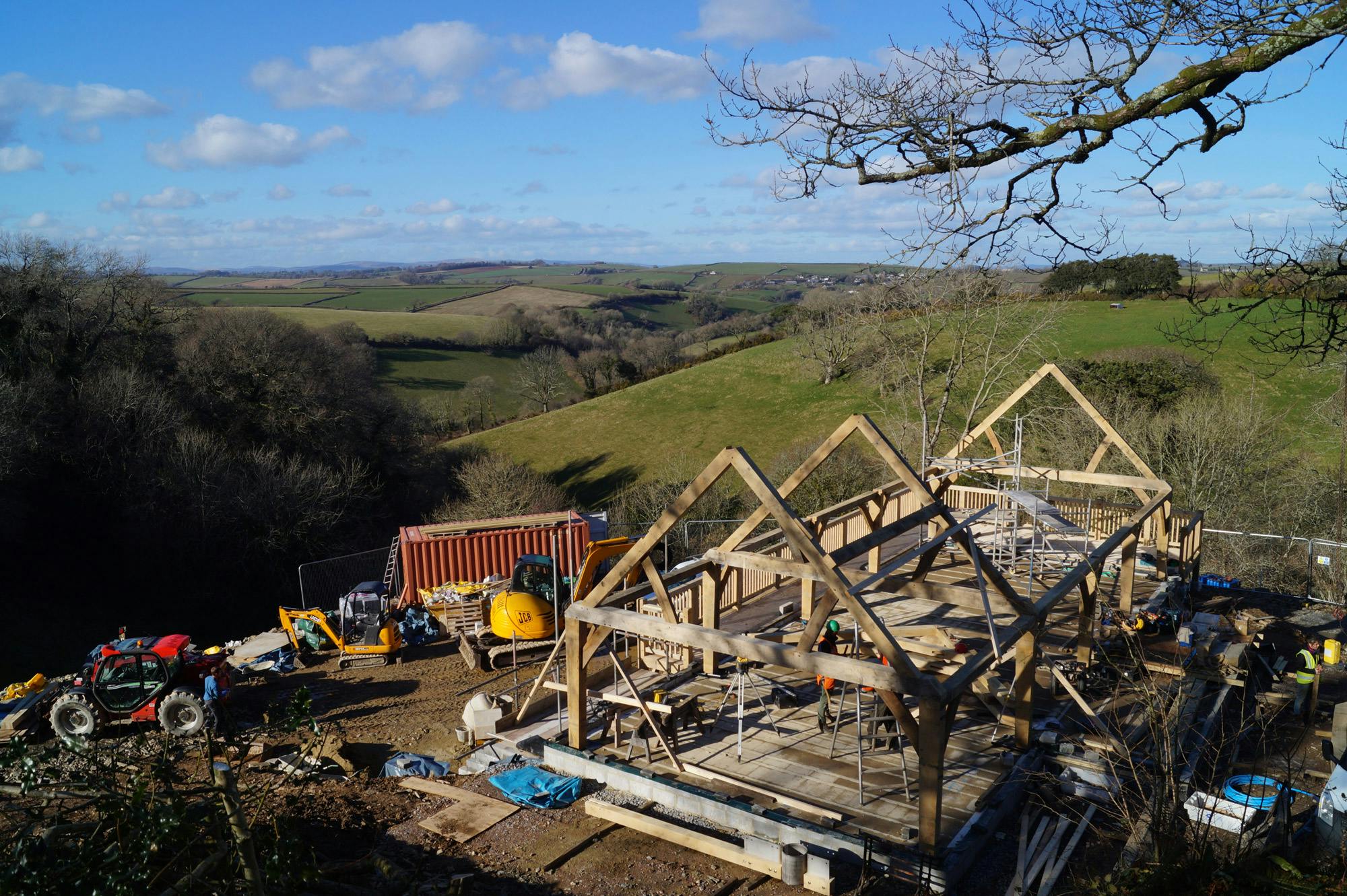 An oak frame being installed on a steep slope in the countryside