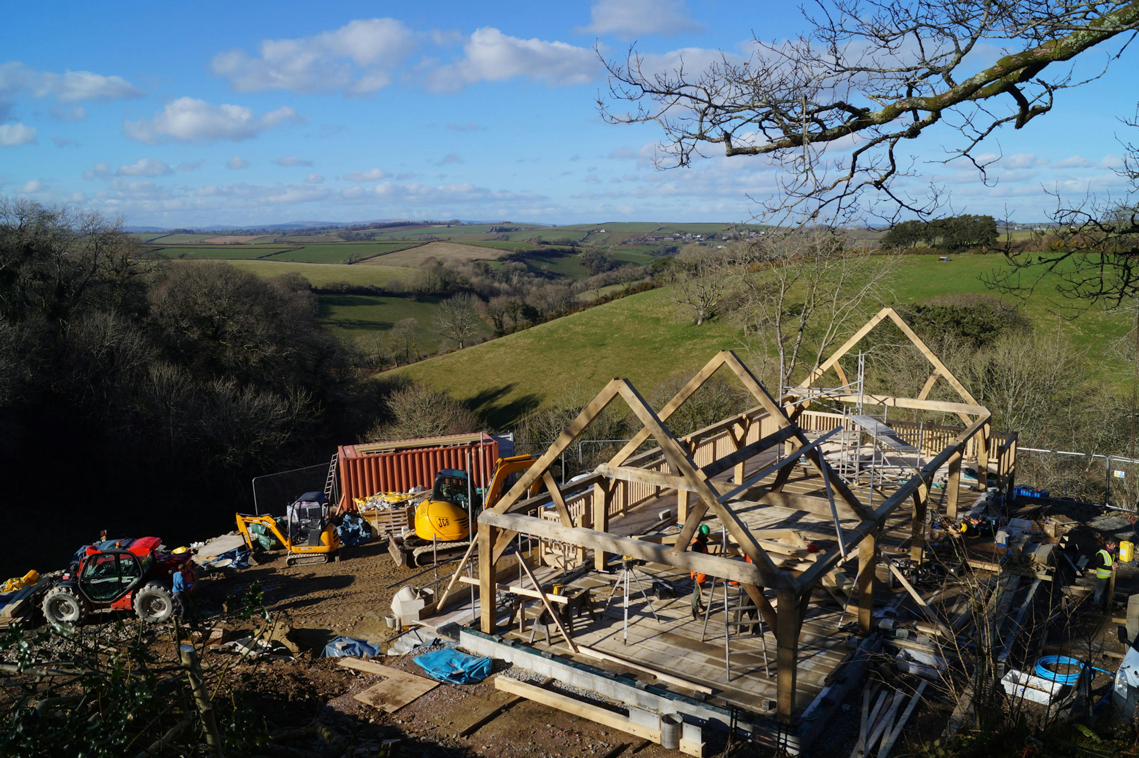 An oak frame being installed on a steep slope in the countryside