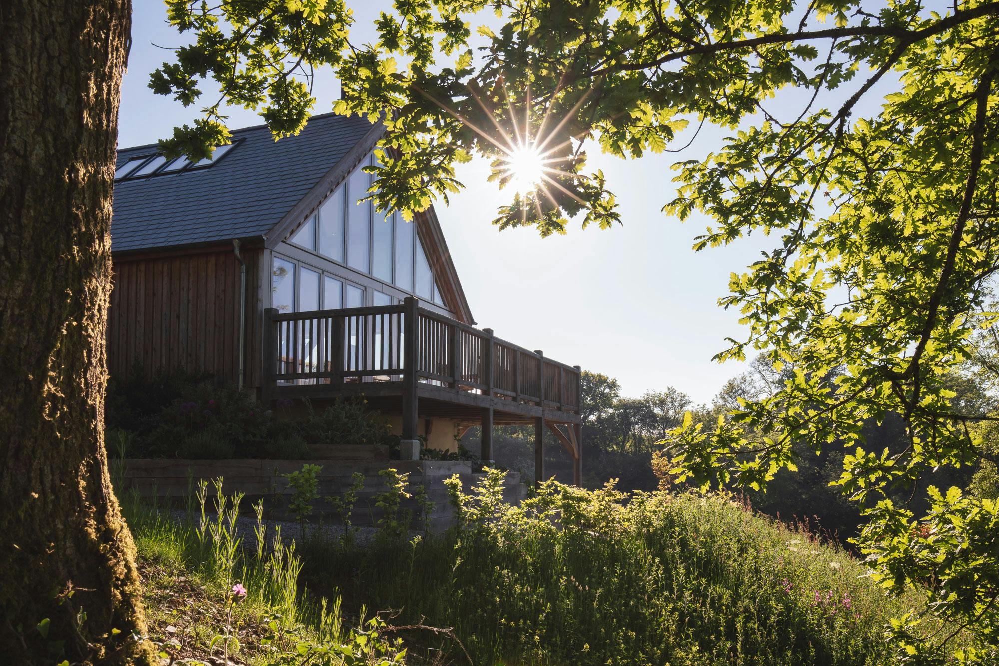 A timber clad oak framed home with a glazed gable end and a balcony in the countryside