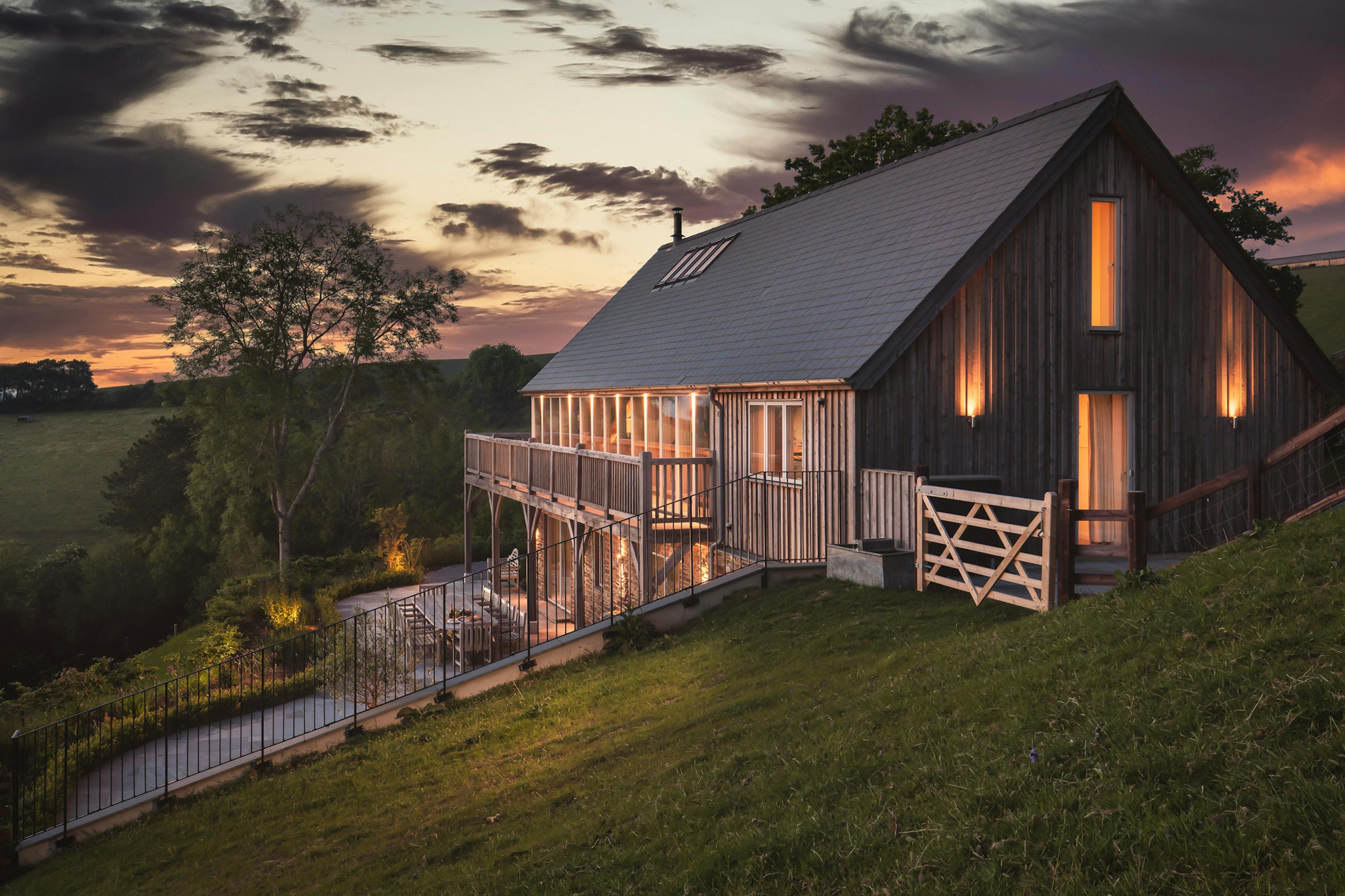 A timber clad oak framed home with balcony in the twilight