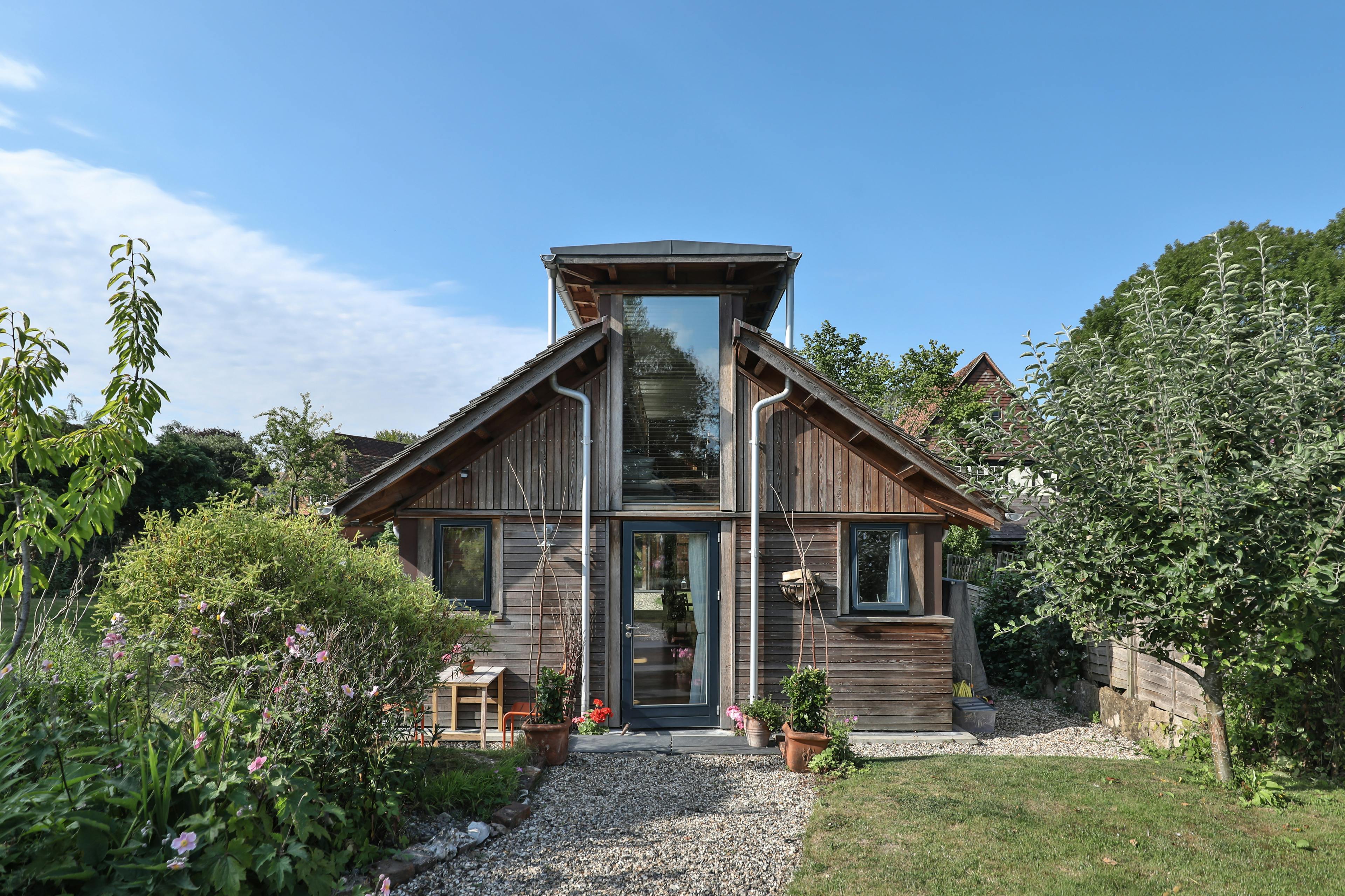 The front of a Douglas fir framed building with cedar cladding and oak shingles with a garden around it