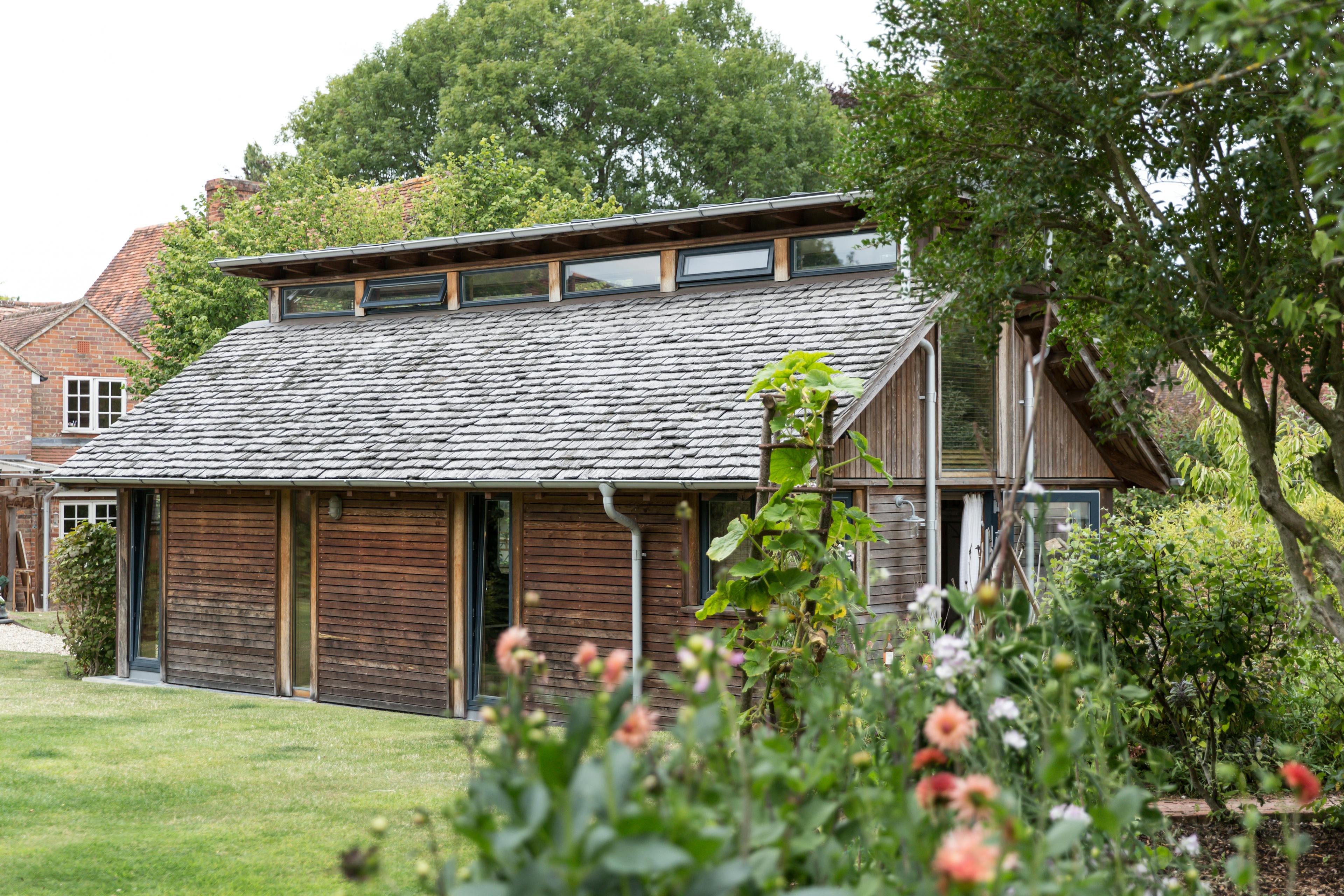 The side of a Douglas fir framed building with cedar cladding and oak shingles with a garden around it