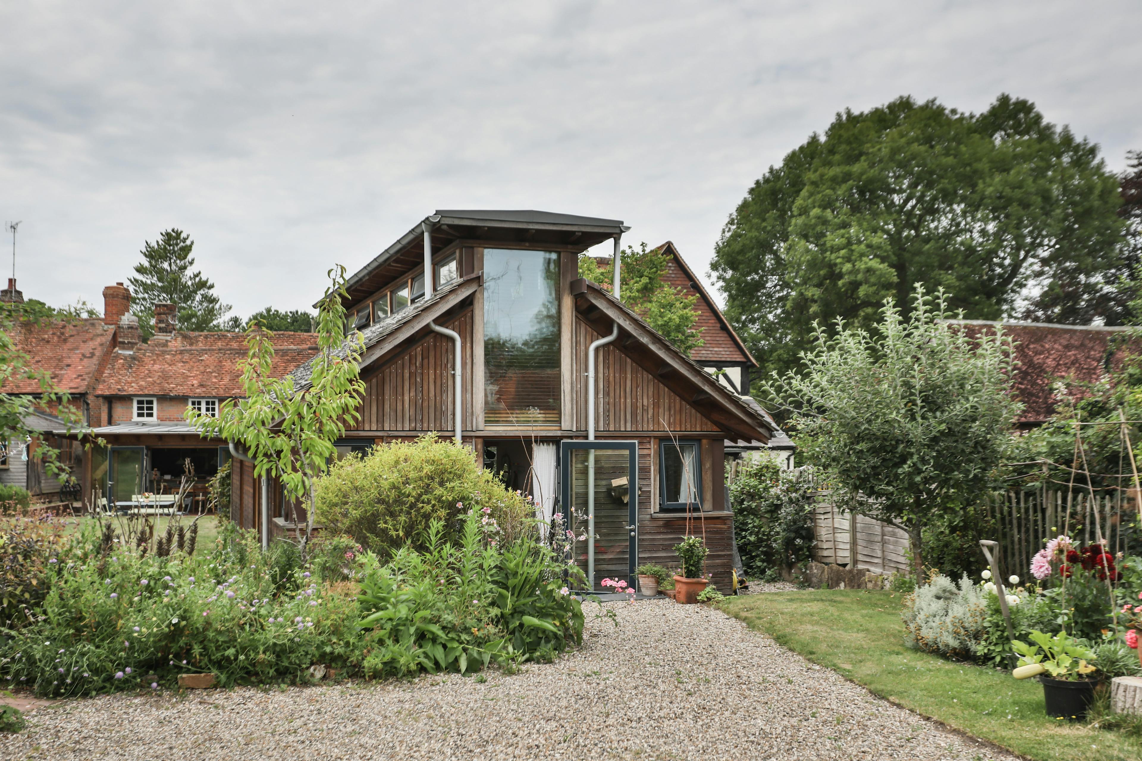 The front of a Douglas fir framed building with cedar cladding and oak shingles with a garden around it