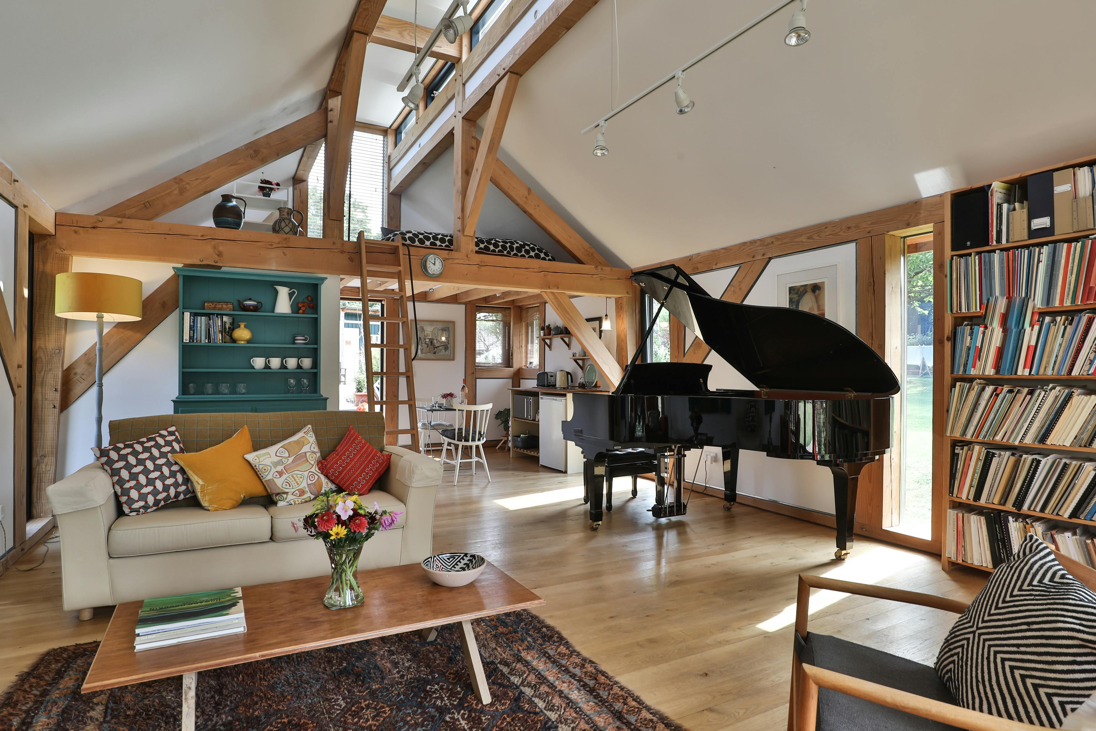 Sofas and a black grand piano in an open plan Douglas fir framed living room