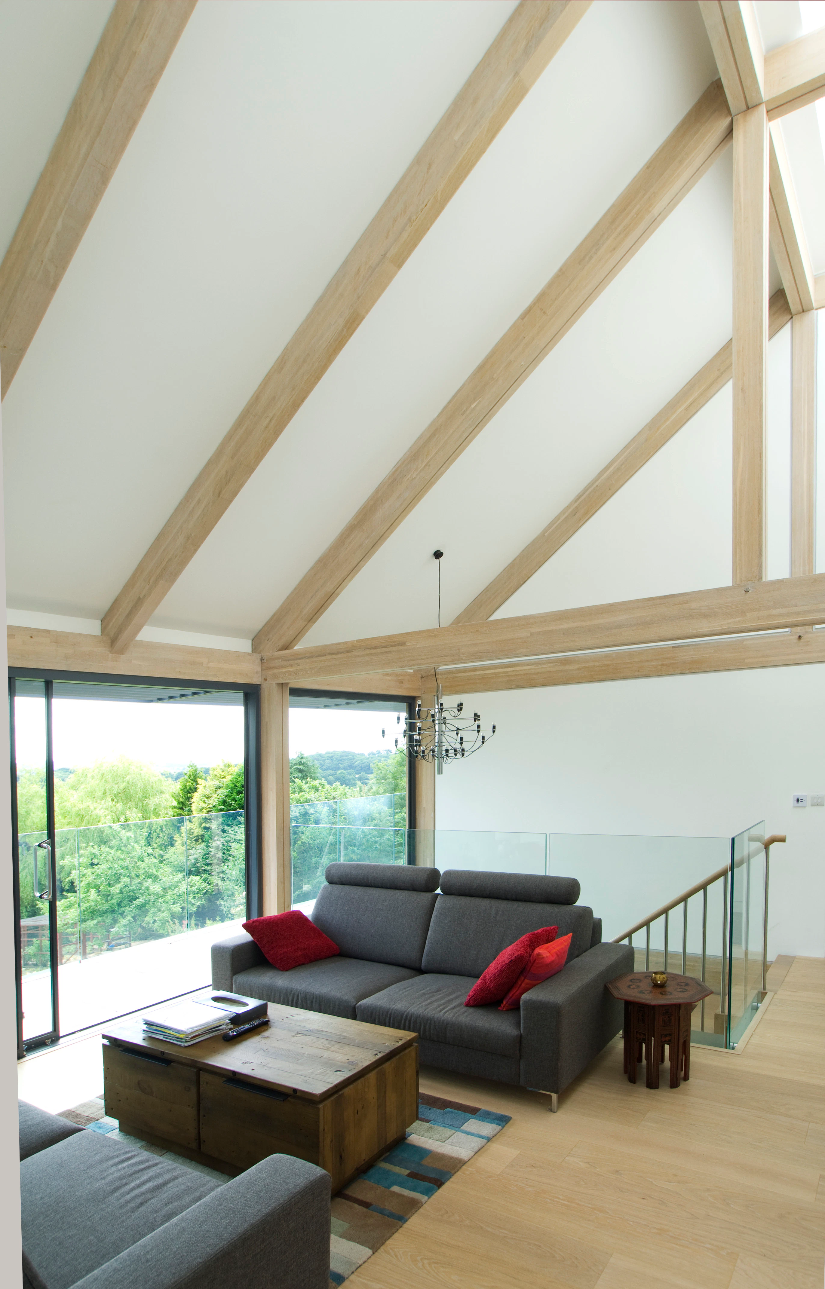 A mezzanine living room with sofas and views of the garden in an oak glulam framed house