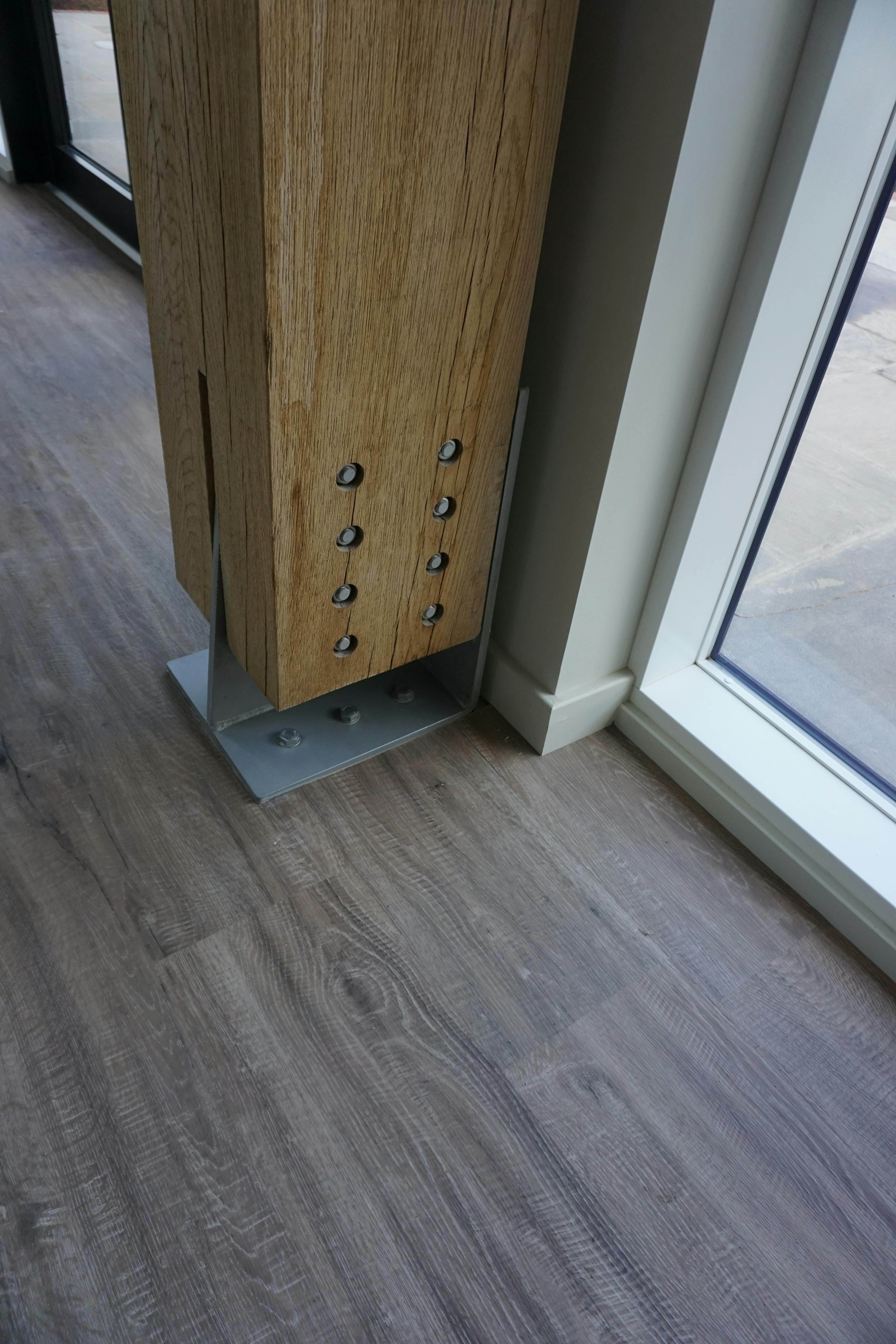 A steel foot post connected to the bottom of an oak post with steel bolts to hold it in place