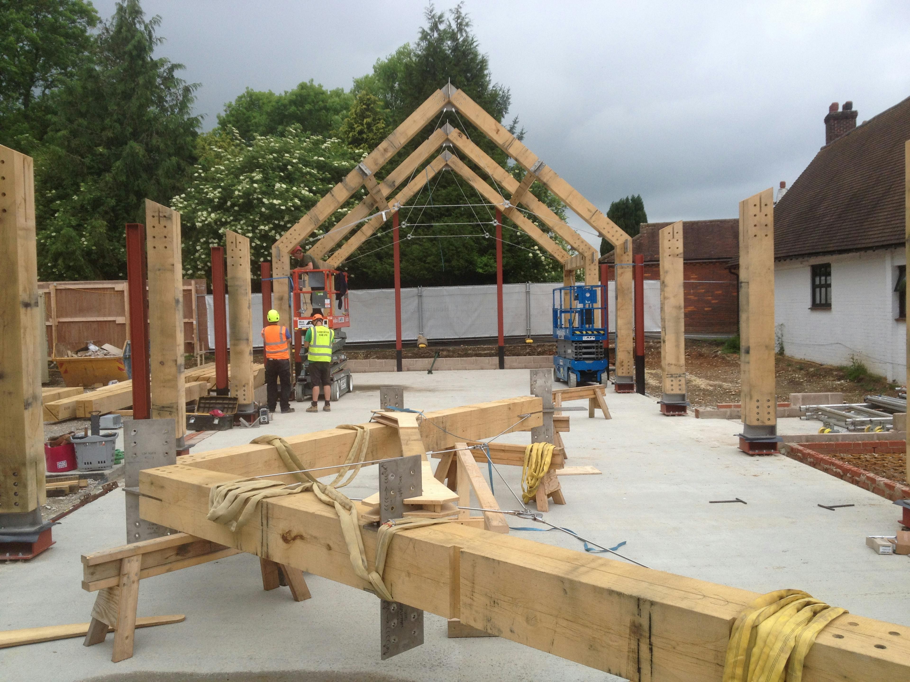An oak frame  half way through being installed on a construction site