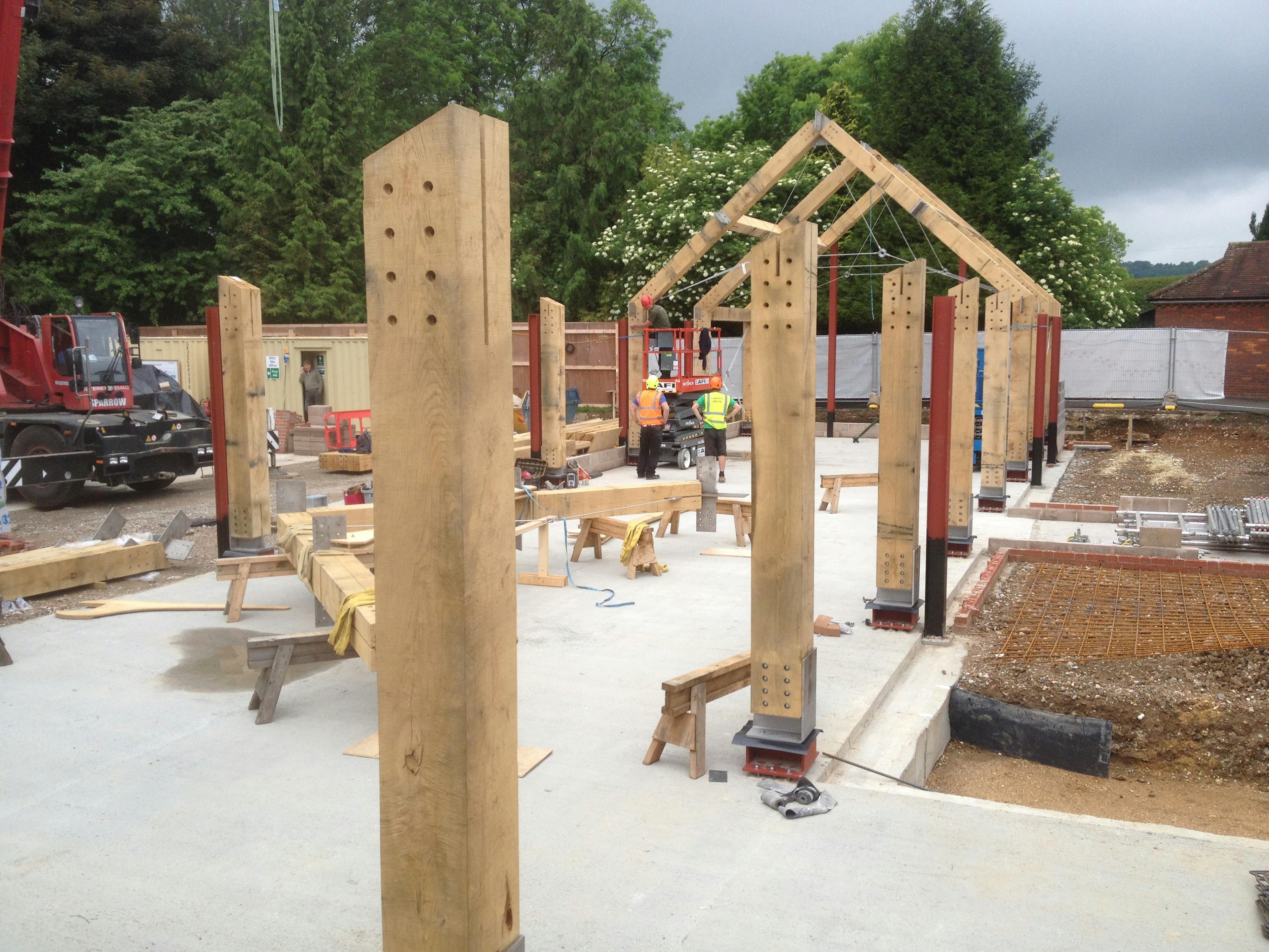 An oak frame half way through being installed on a construction site