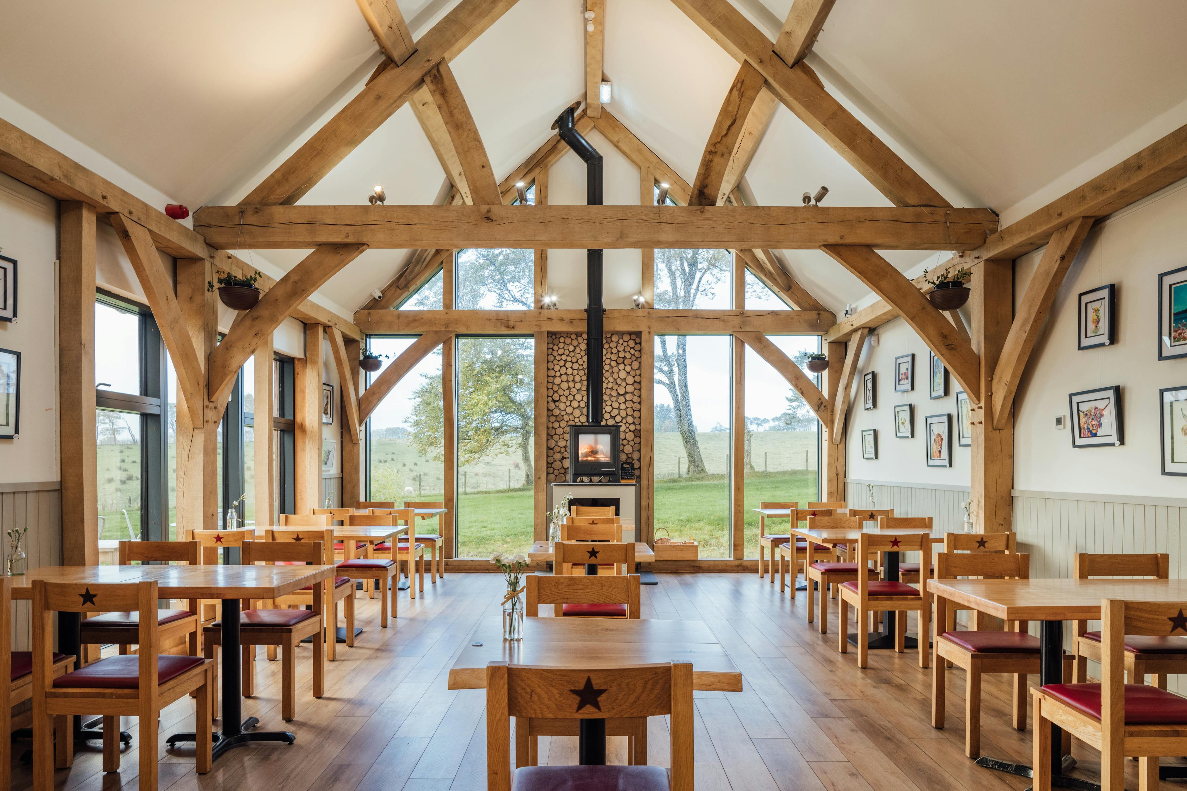 An oak framed cafe with a log burner under a vaulted ceiling