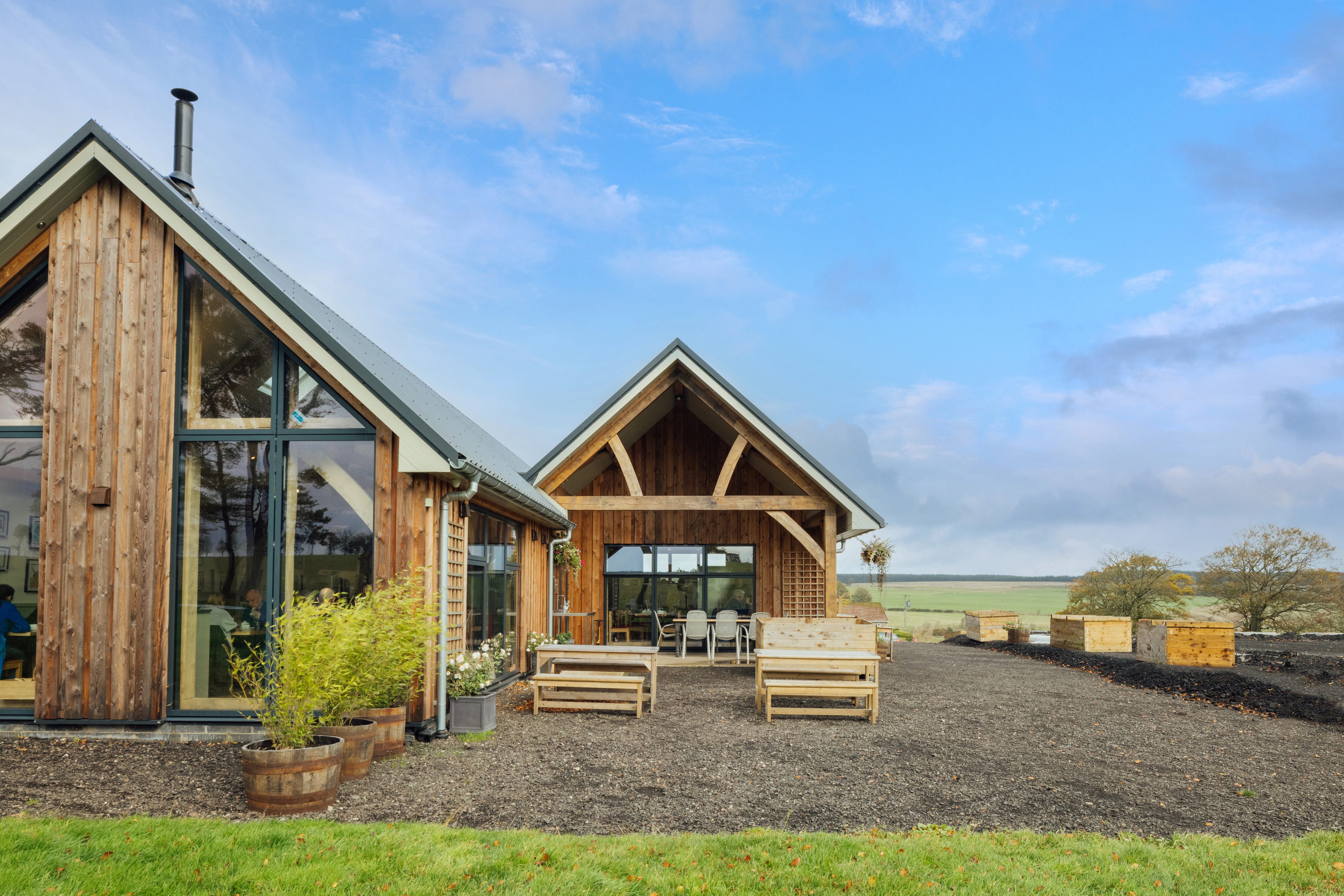 The rear of a 3 barn timber clad oak framed farm shop and cafe 