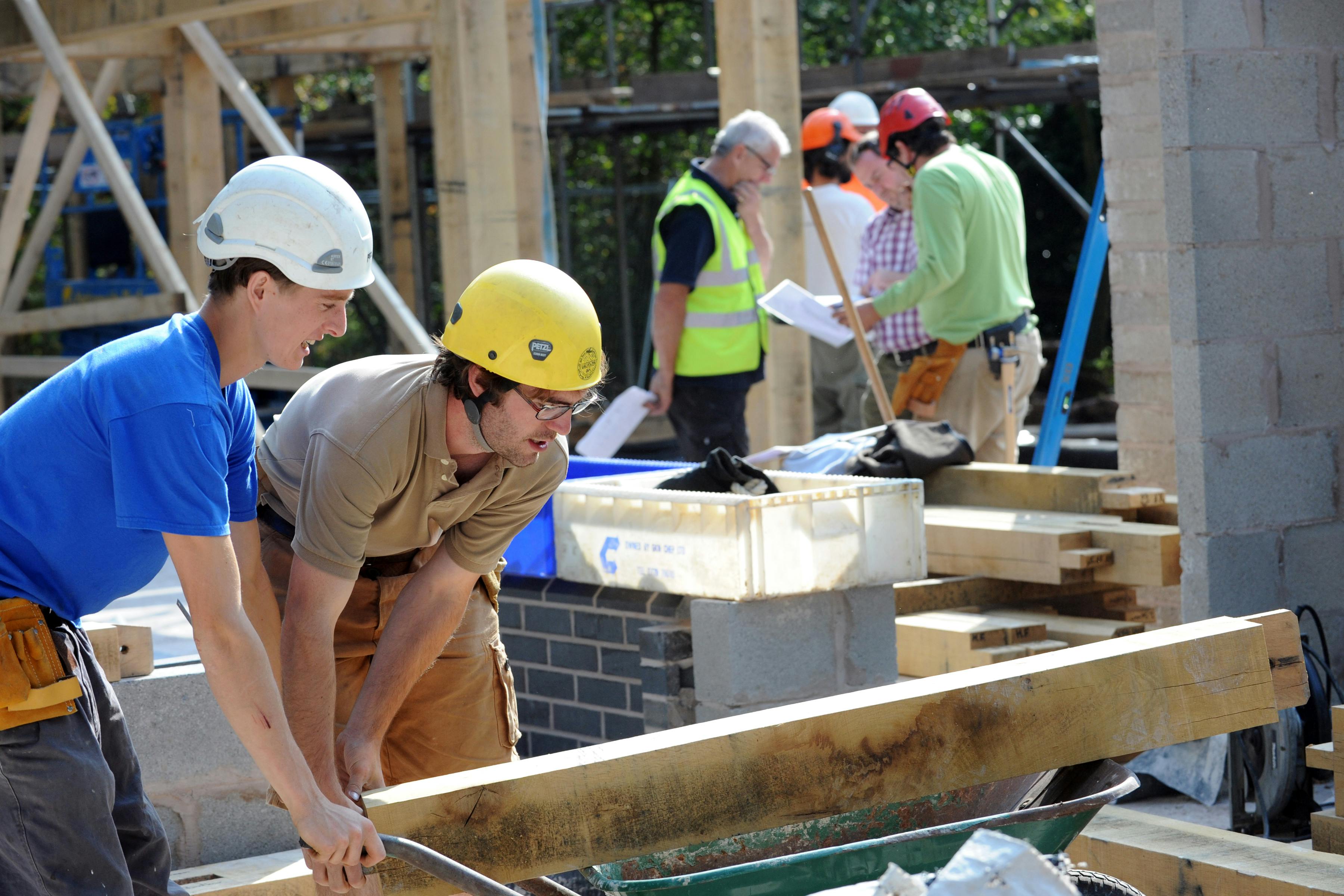 Workers in hard hats on a construction site to install an oak frame for a home