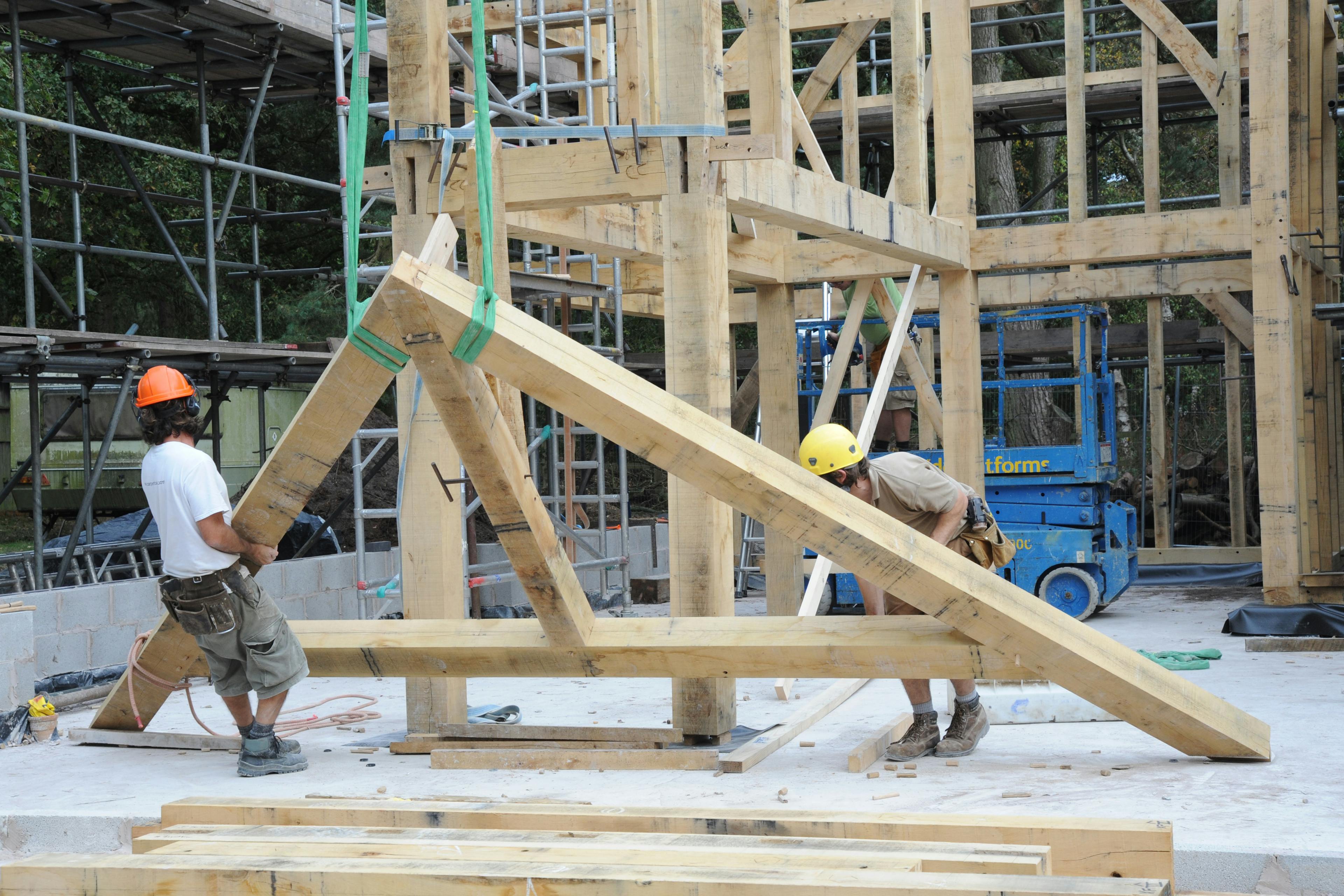 Two workers move a truss during construction of an oak frame home