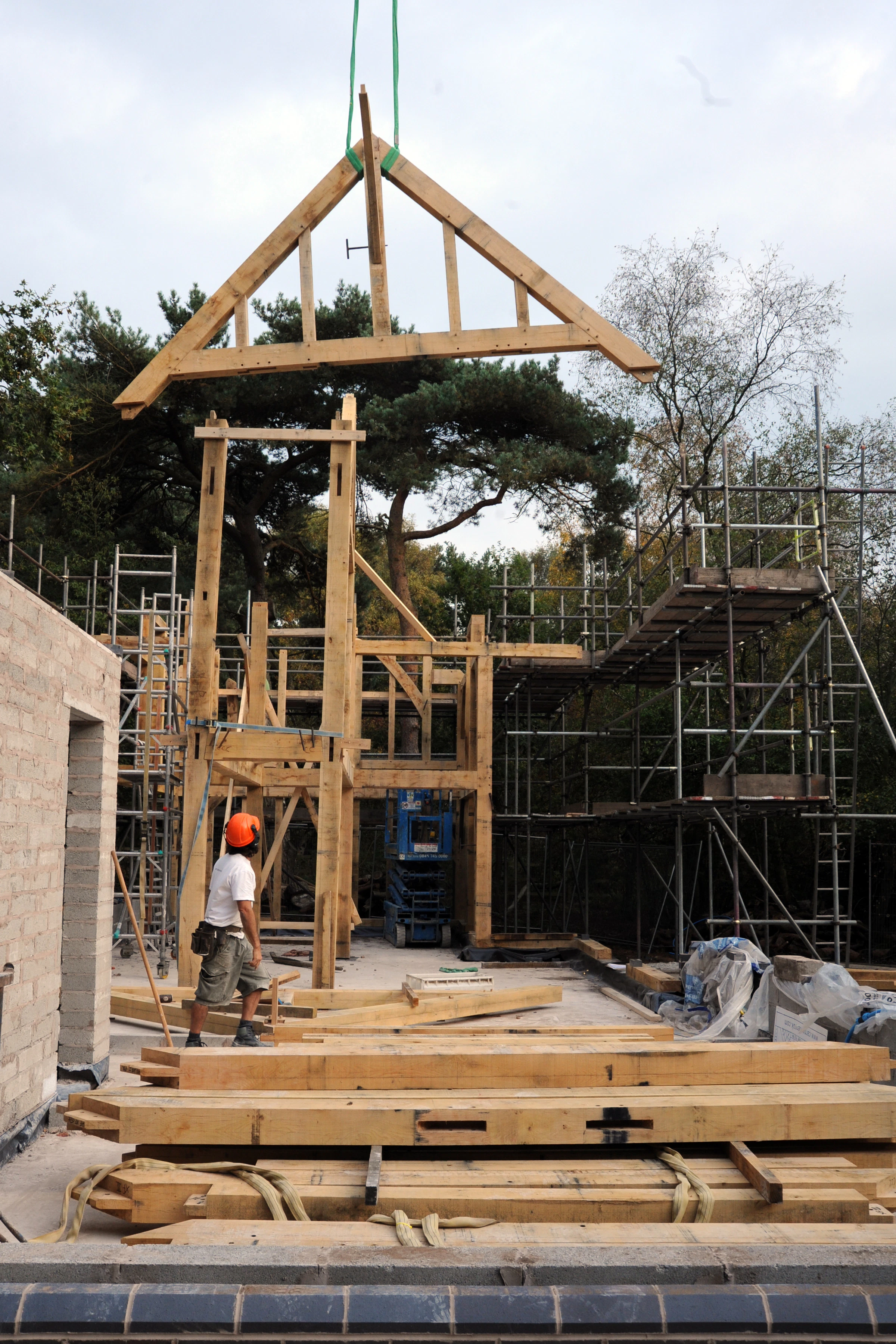 A crane lowers an oak truss during construction of an oak framed home