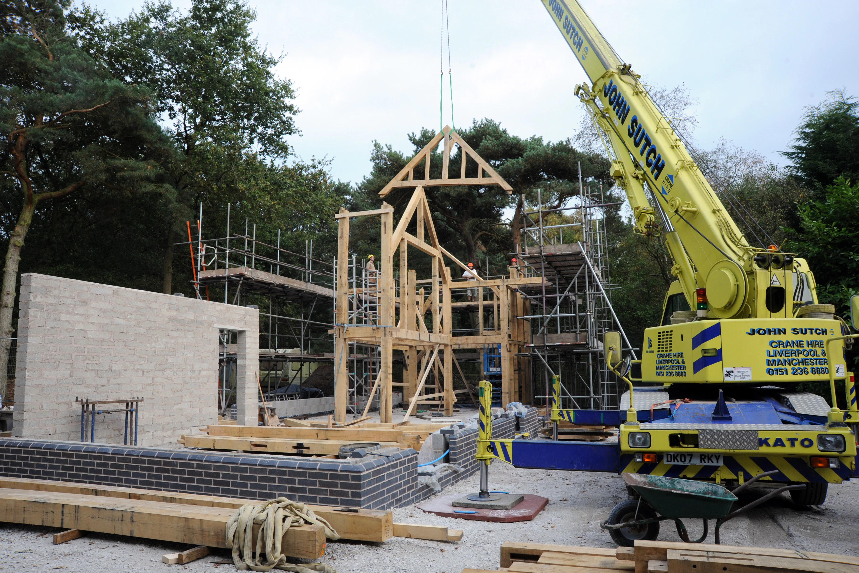 A crane lowers an oak truss during construction of an oak framed home