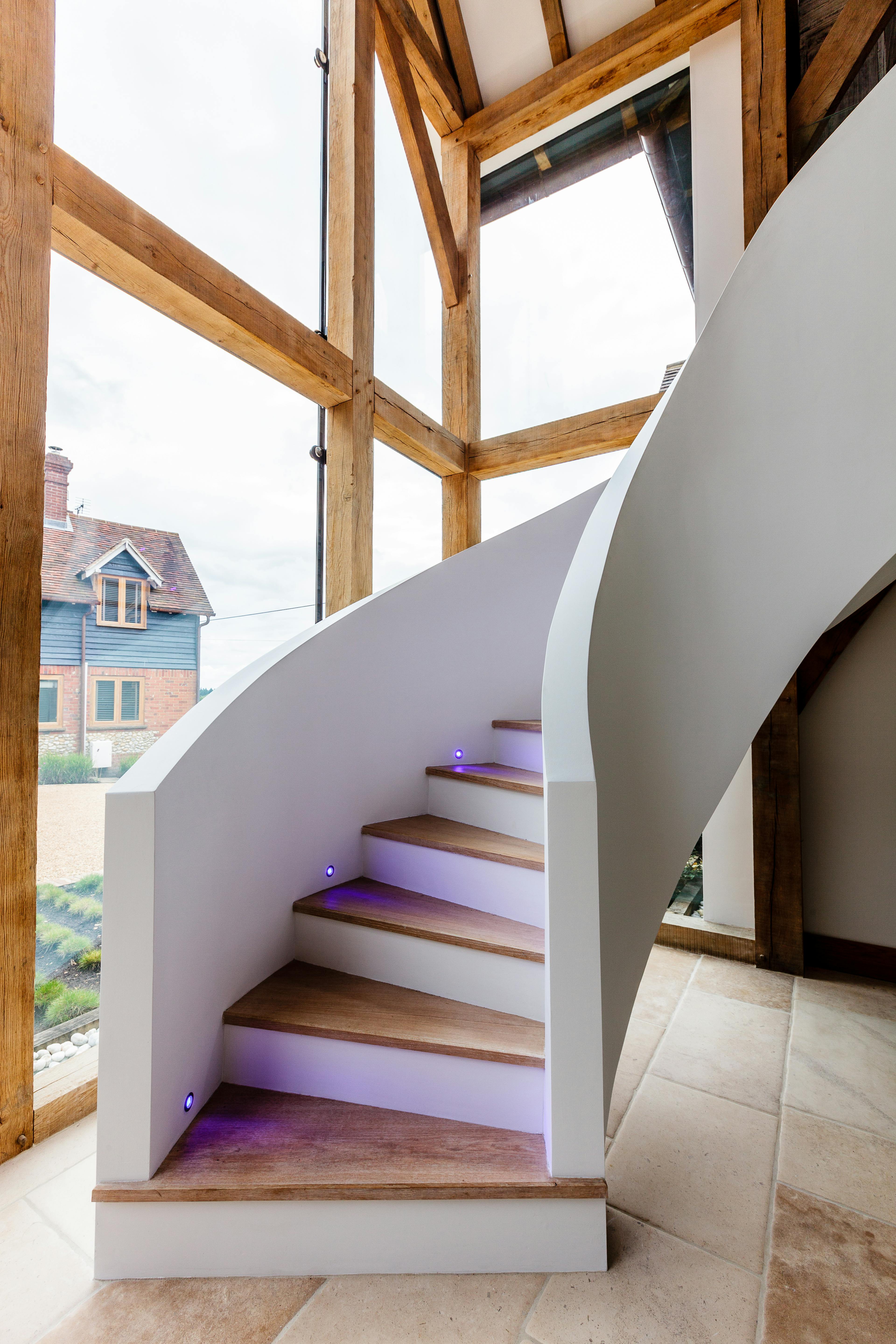 A double height entranceway with large oak framed glazed end and spiral staircase