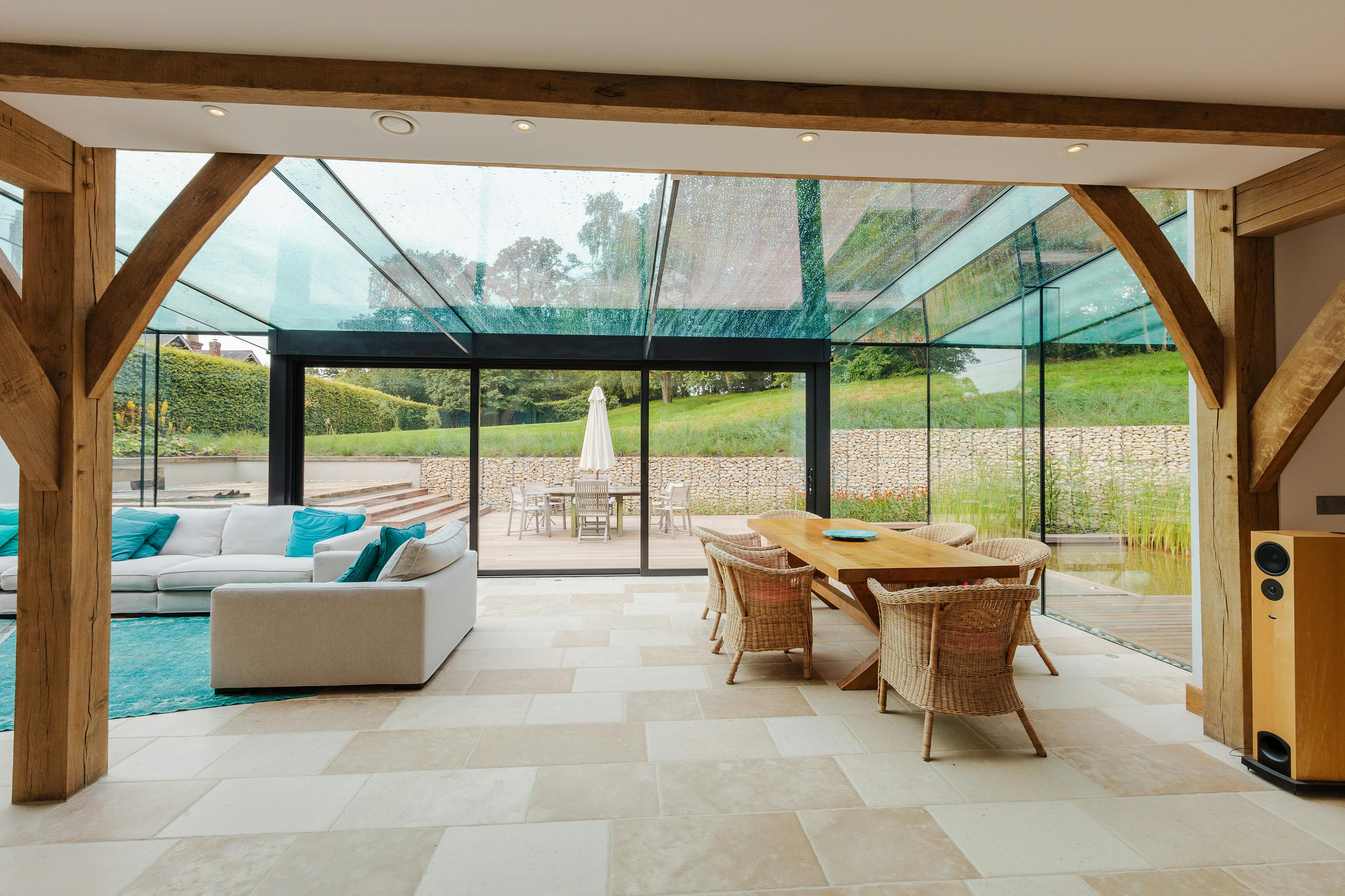 An oak framed living area with dining table and chairs and sofas with a modern glazed extension
