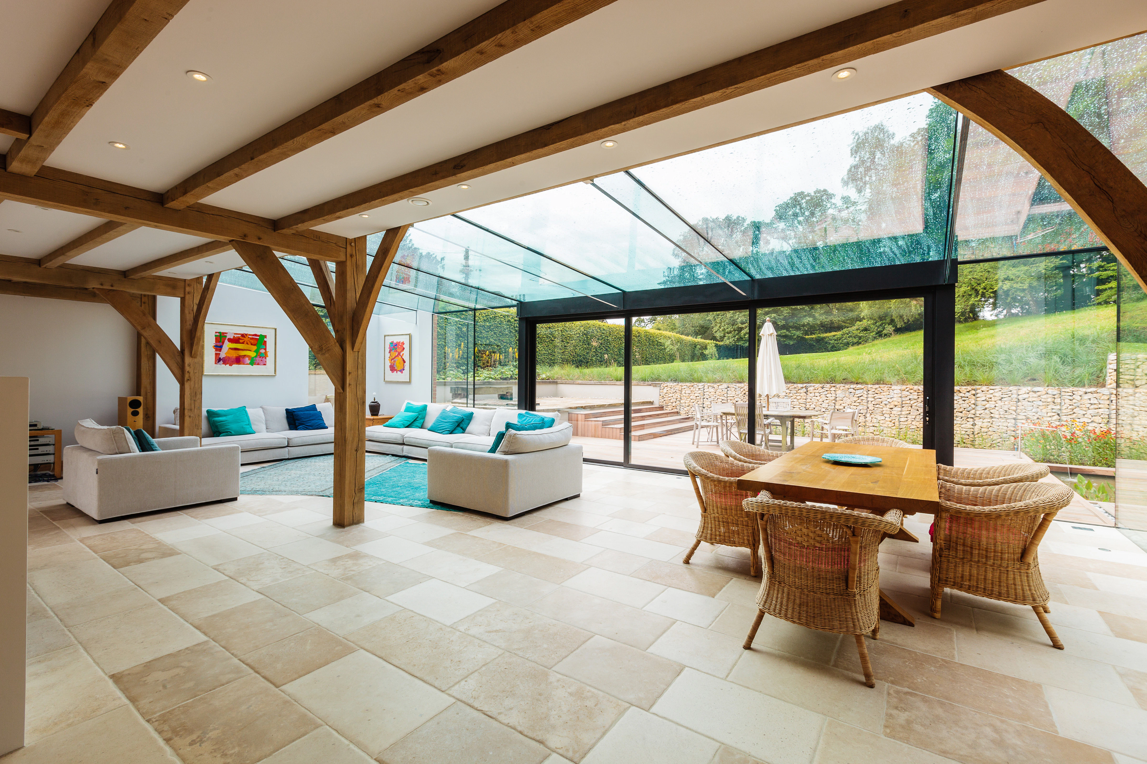 An oak framed living area with dining table and chairs and sofas with a modern glazed extension