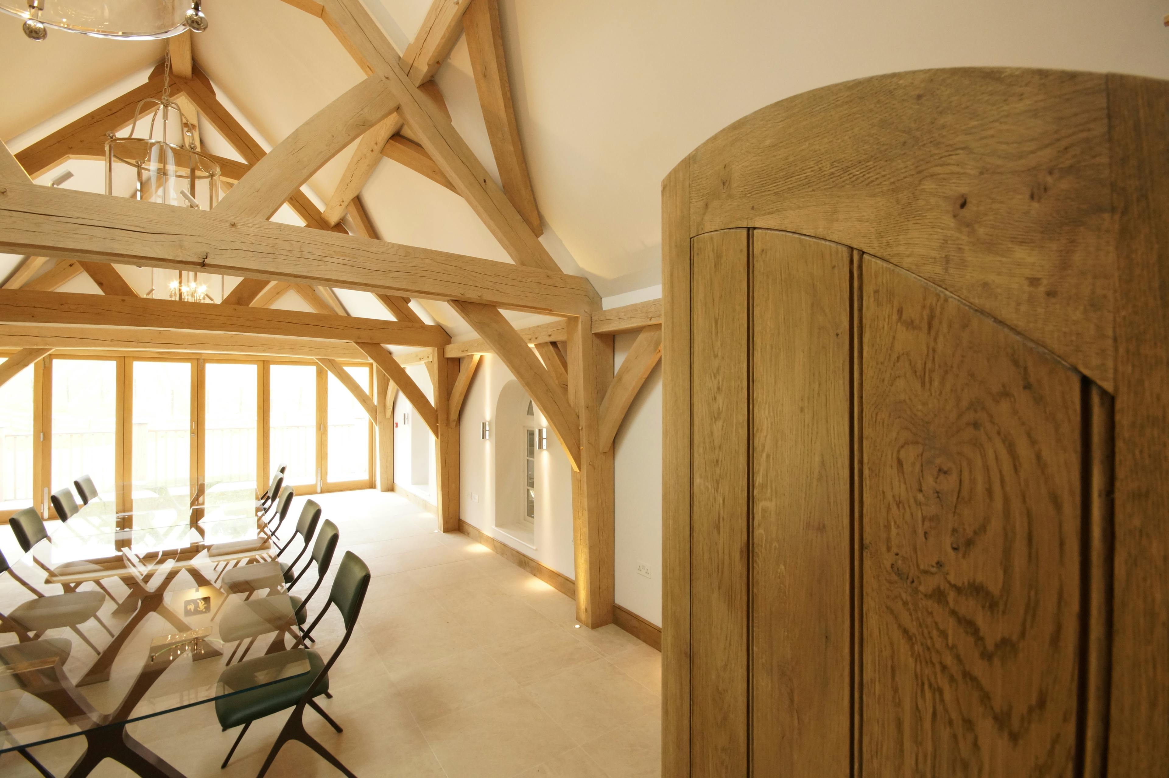 A table and chairs in an oak framed room with two trusses