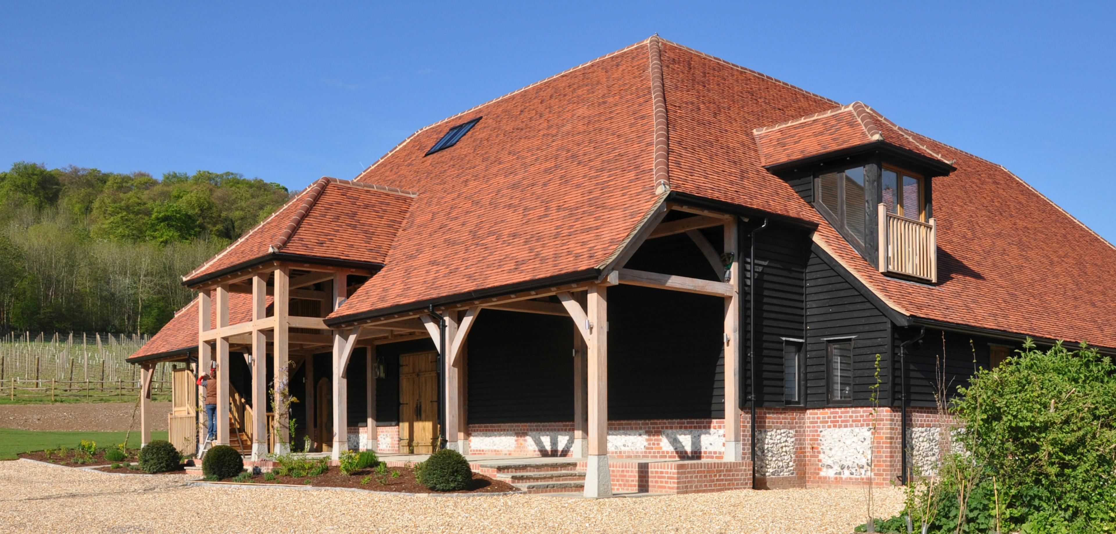 A large winery building with red roof tiles and oak framed balconies and veranda